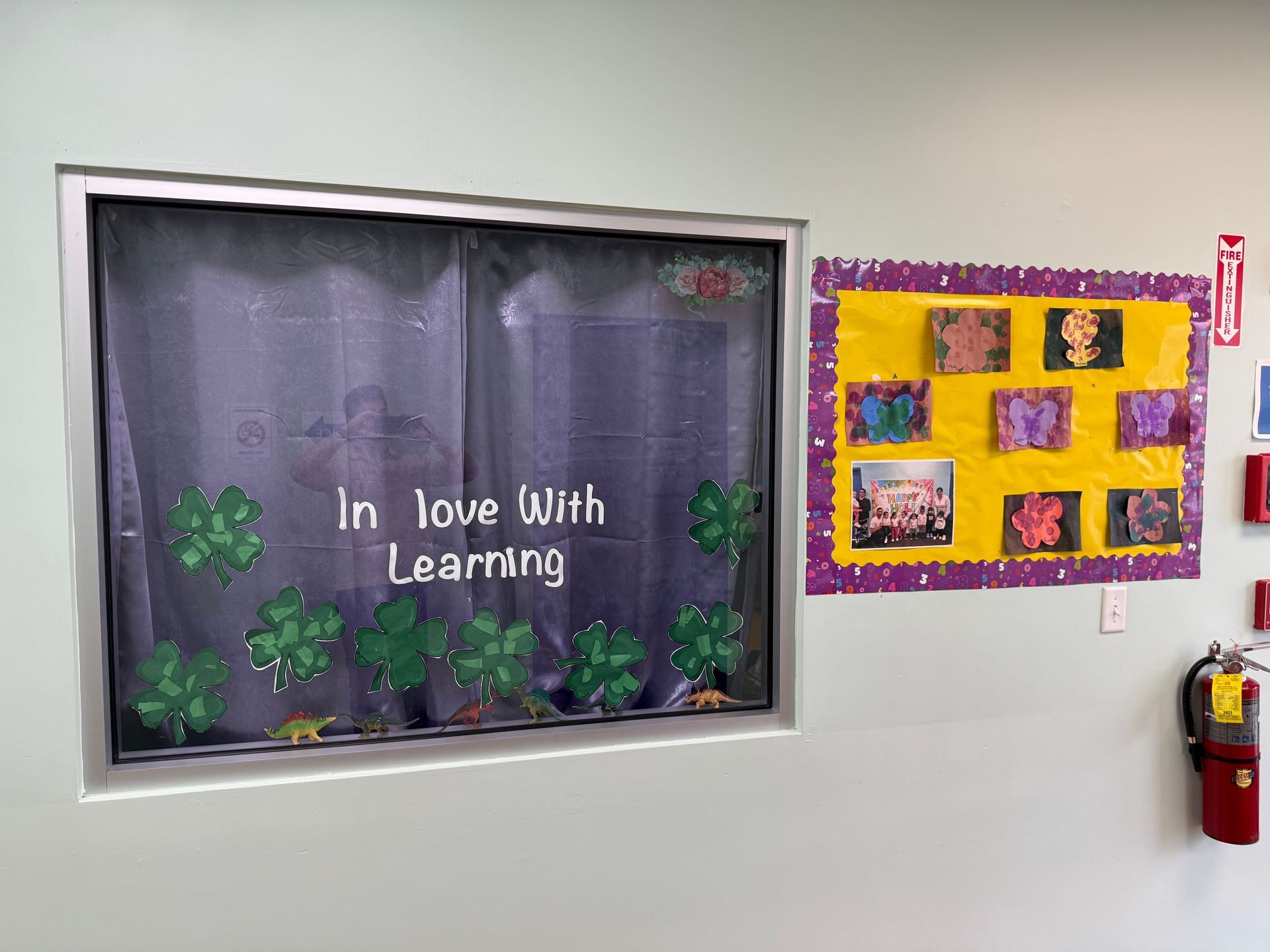 A classroom window decorated with green shamrocks and the phrase 