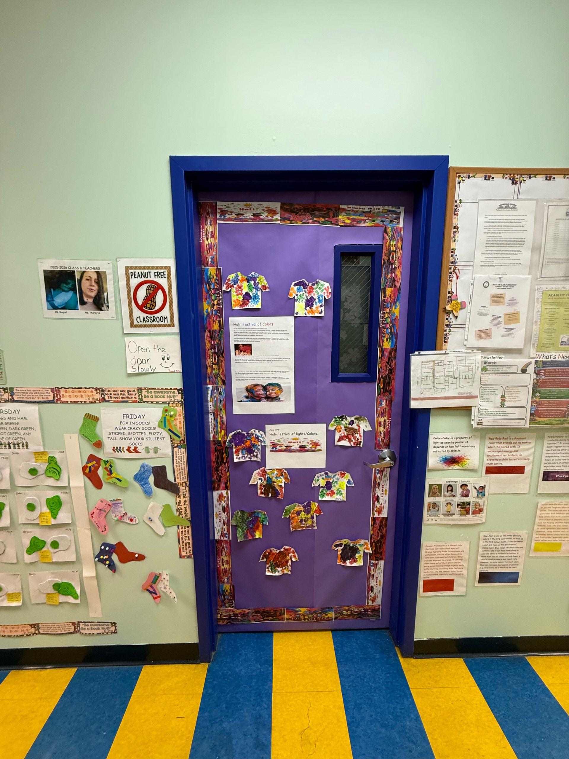 A purple classroom door decorated with colorful cutouts, surrounded by school notices and student artwork on the walls.