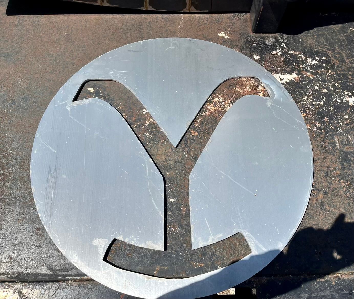 Circular metal cutout of a Y brand symbol