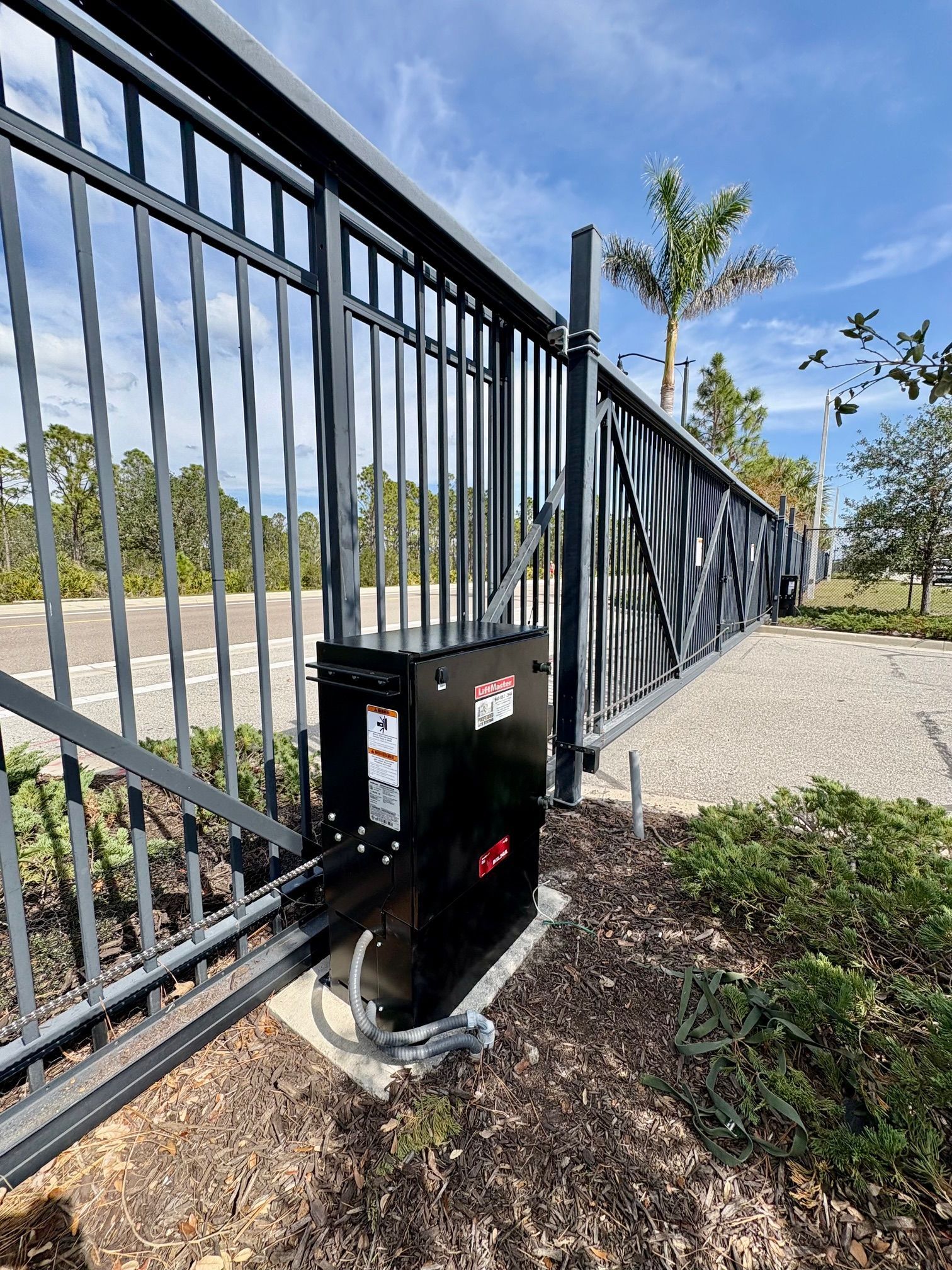 Black automatic gate opener on gray metal gate.