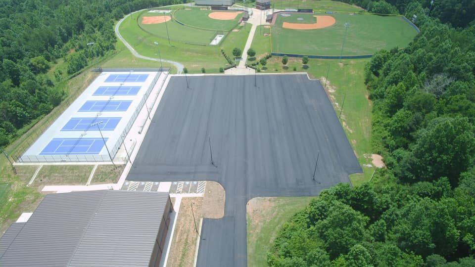 Overhead view of outdoor sports complex with tennis courts, parking area, and baseball fields.
