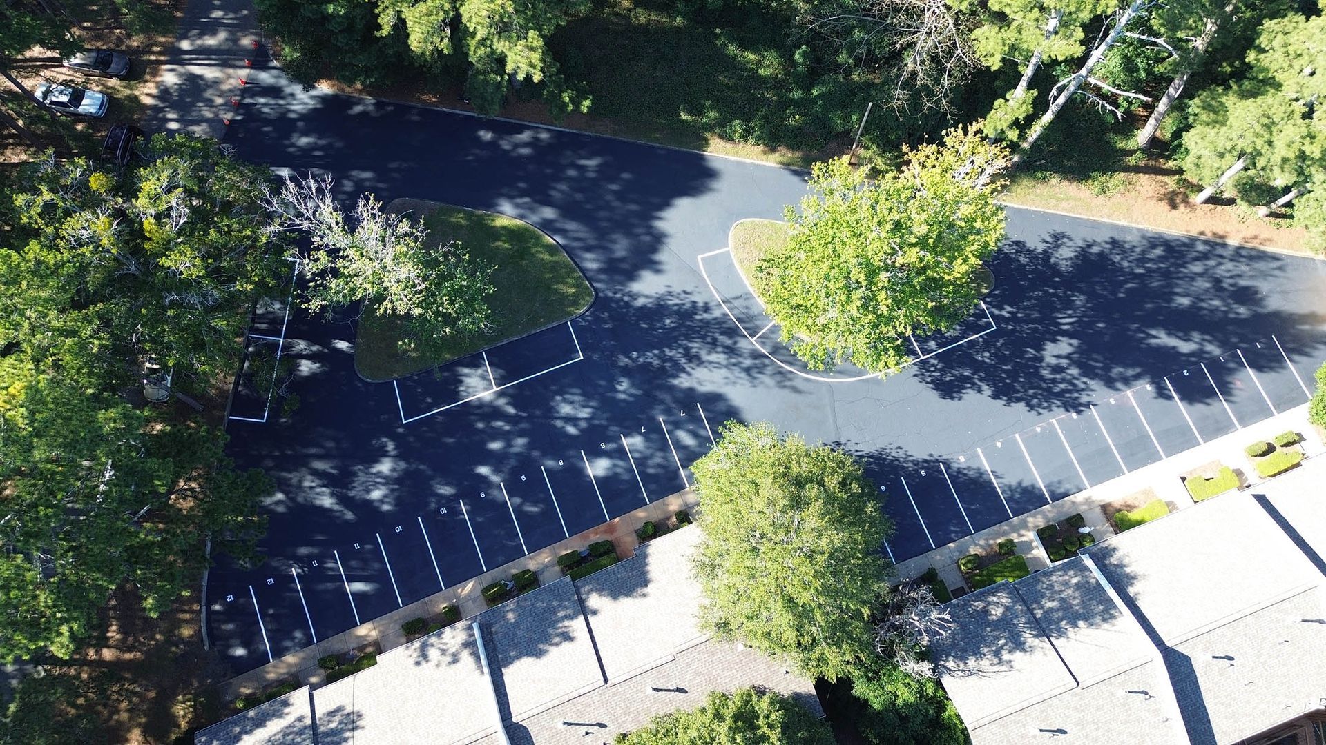 Aerial view of a parking lot with marked spaces and several trees.