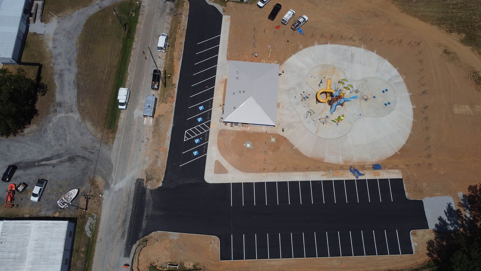 Aerial view of a parking lot, playground, and building with cars parked nearby, all outdoors.