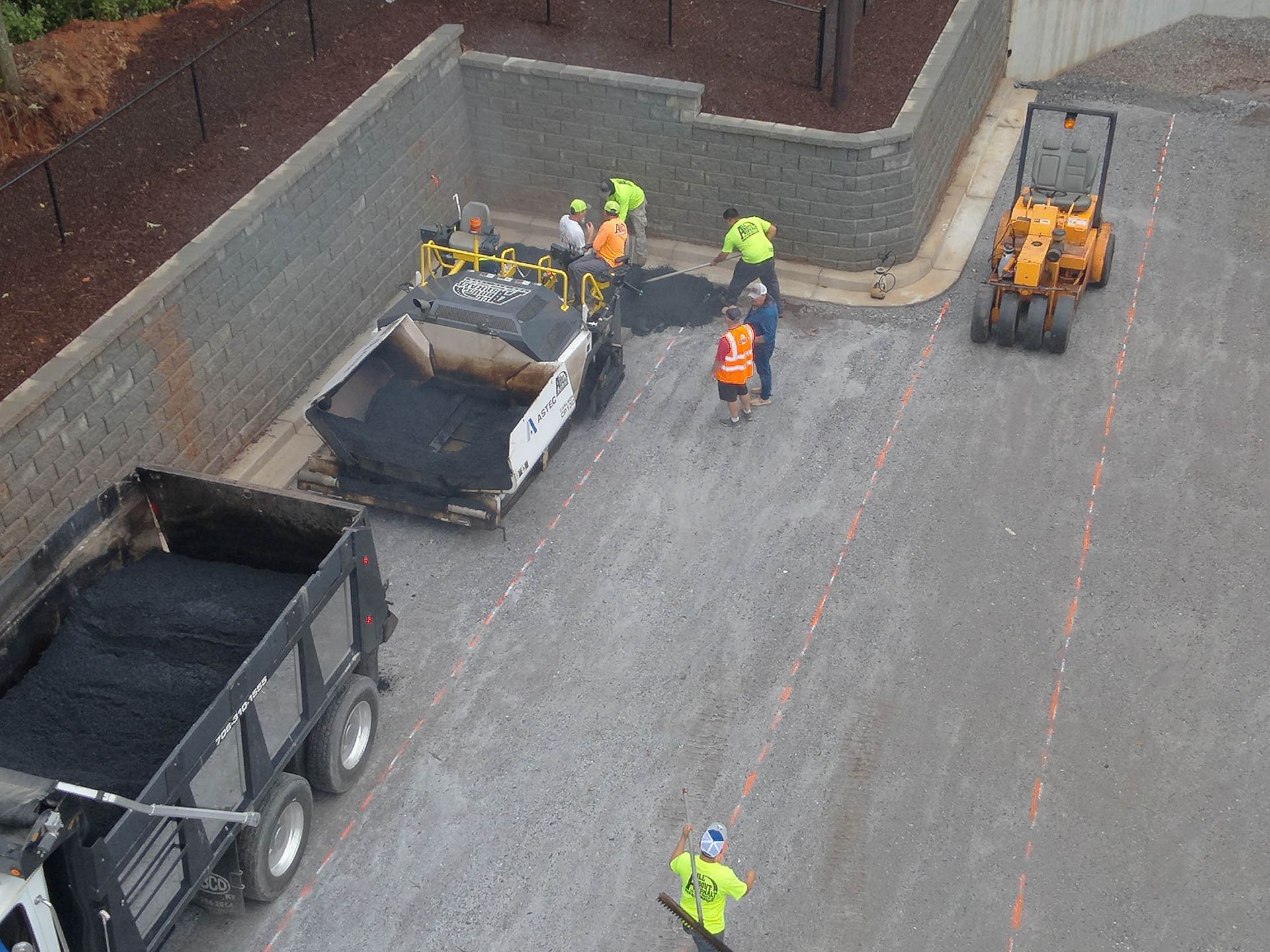 Road paving in progress. Workers, asphalt paver, dump truck, and compactor machine on a road.