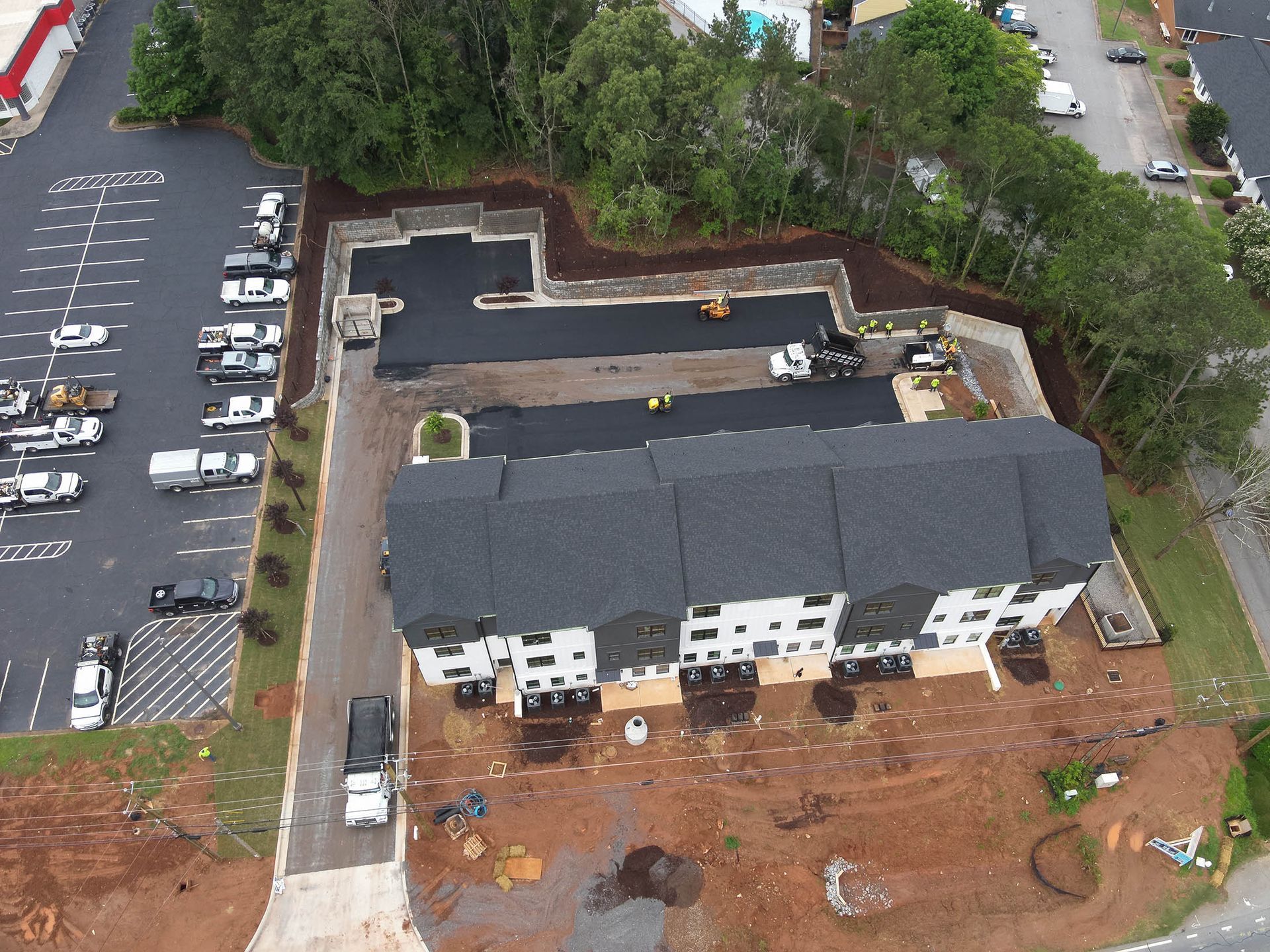 Aerial view of apartment complex under construction with asphalt and parking area.