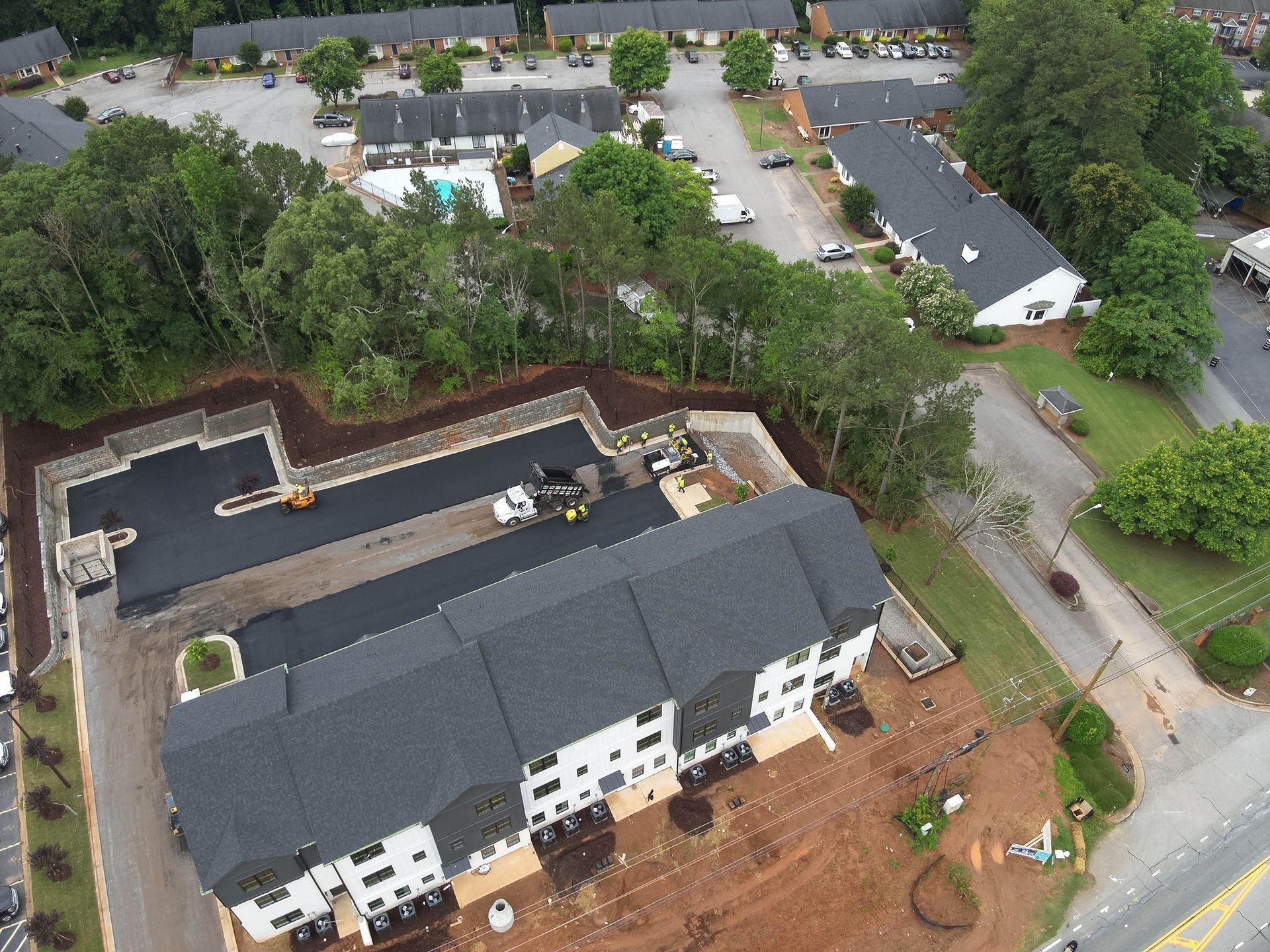 Aerial view of apartment complex undergoing asphalt work.