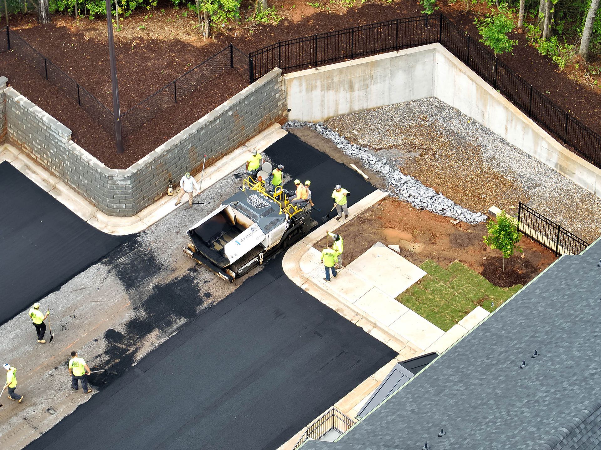 Asphalt paving crew at work, laying dark pavement in a construction area.