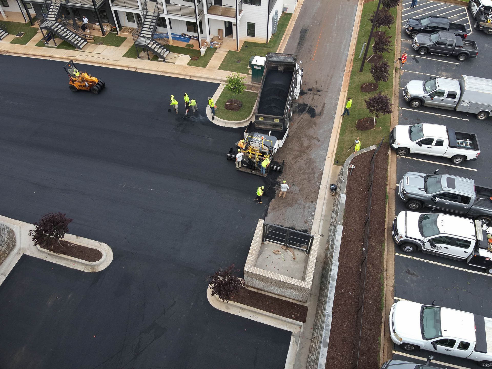 Asphalt paving crew at work, pouring and smoothing fresh asphalt on a parking lot.