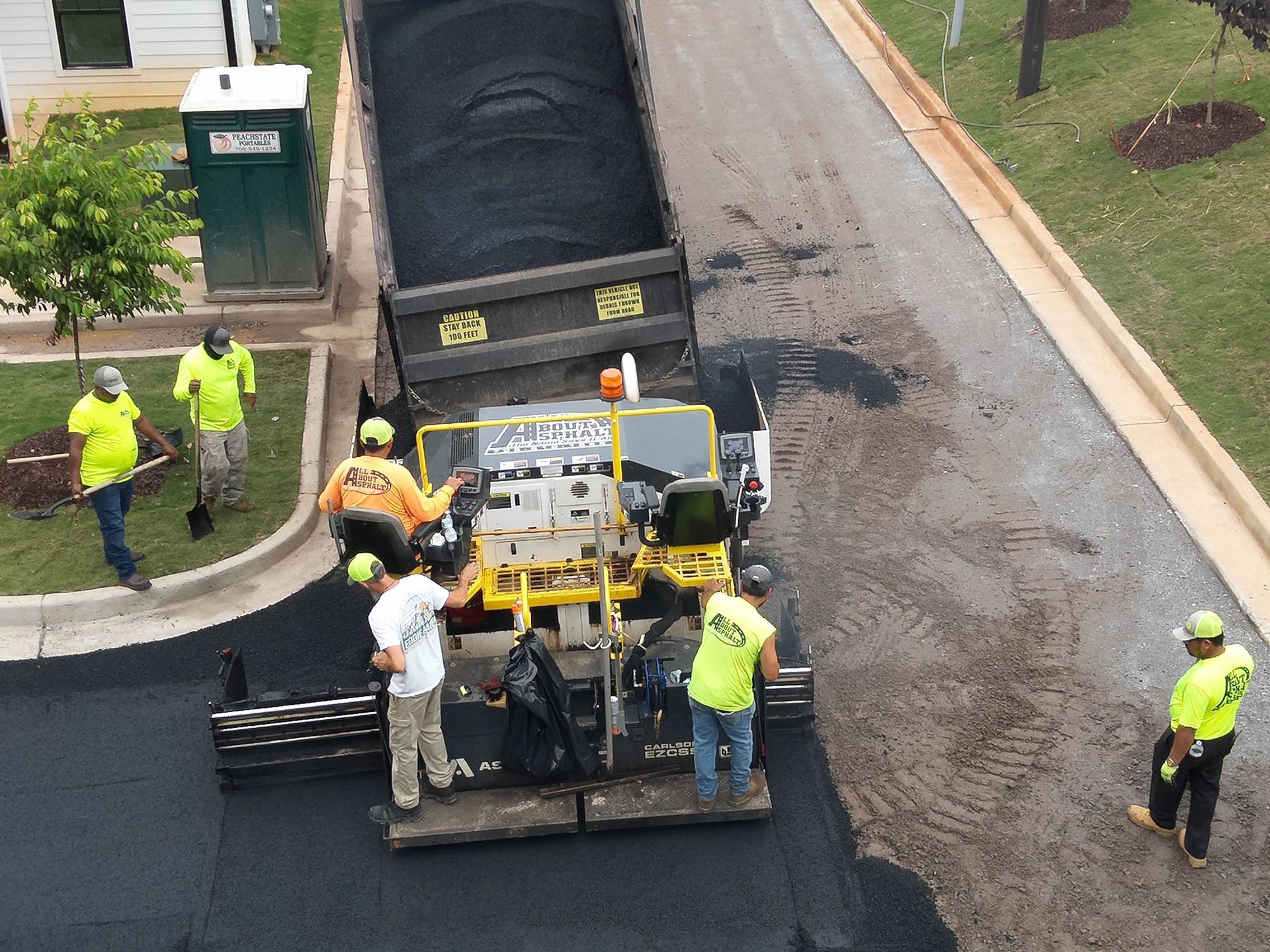 Asphalt paving crew at work. A truck dumping asphalt into a paving machine on a road.