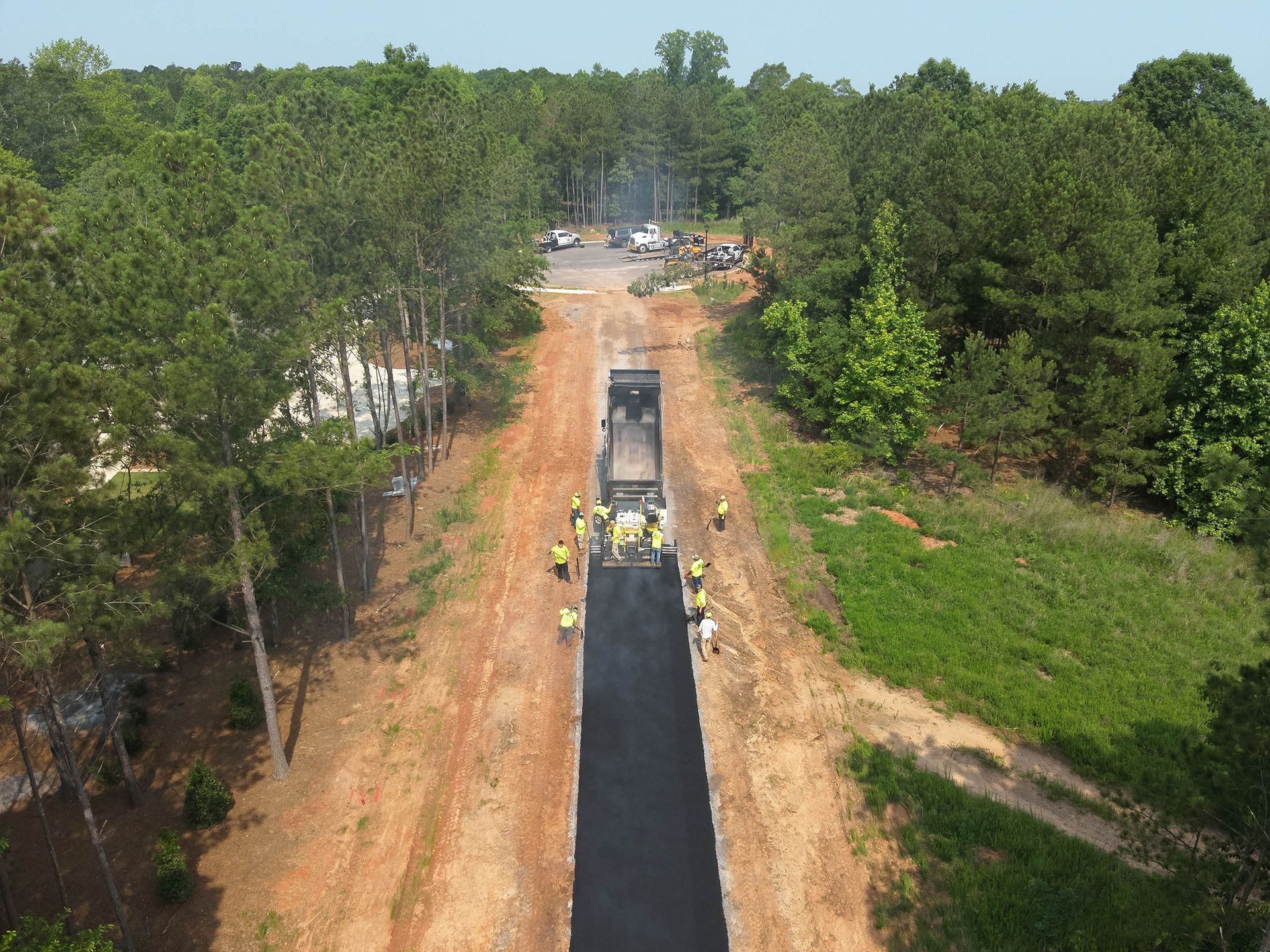Road construction. Workers paving a road through a forest. Asphalt is being laid down by a machine and workers.