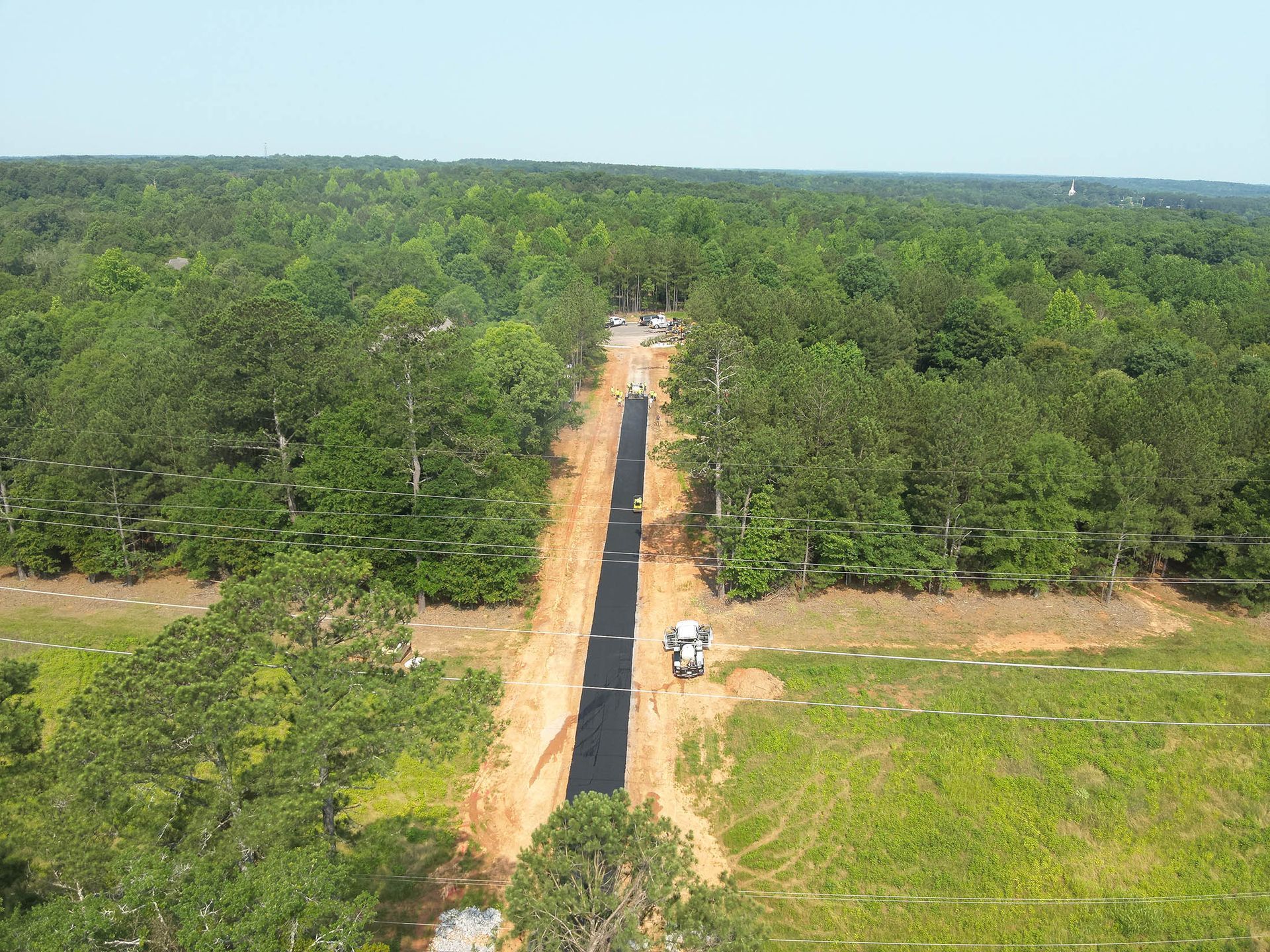 A cleared path through a forest, possibly for utilities, with a construction vehicle visible.