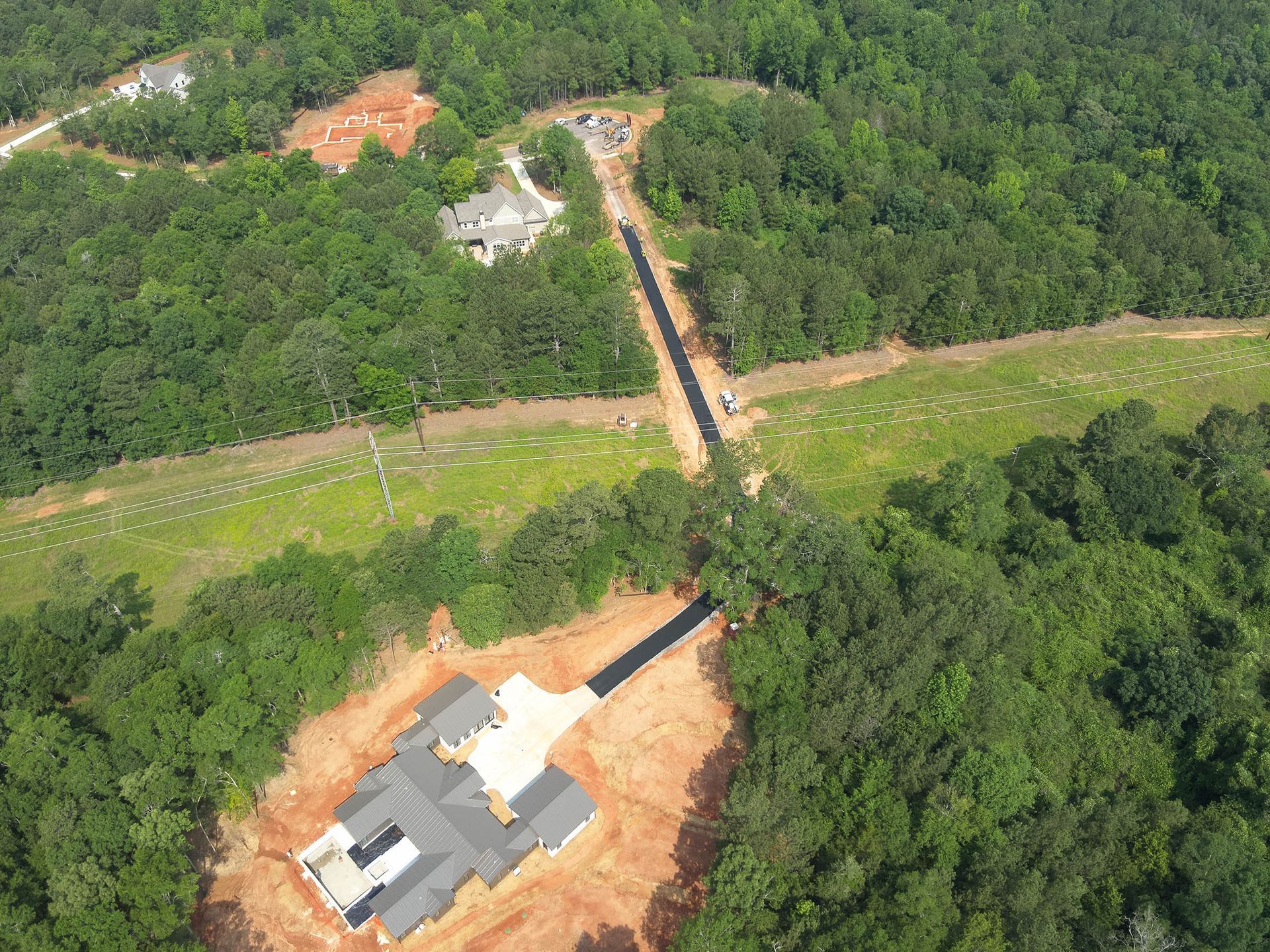 Aerial view of construction site with partially built houses surrounded by forest.
