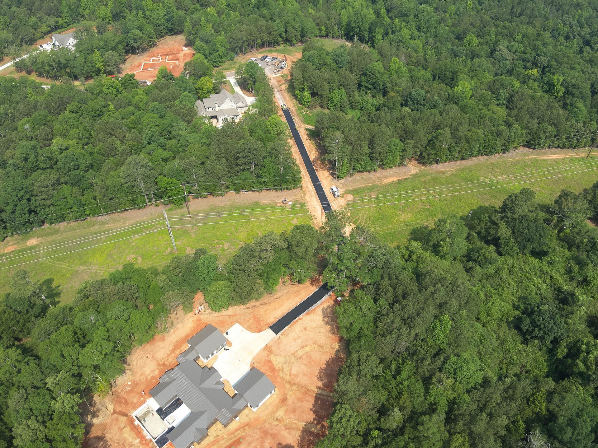 Aerial view of a clearing through a forest with two houses on either side.