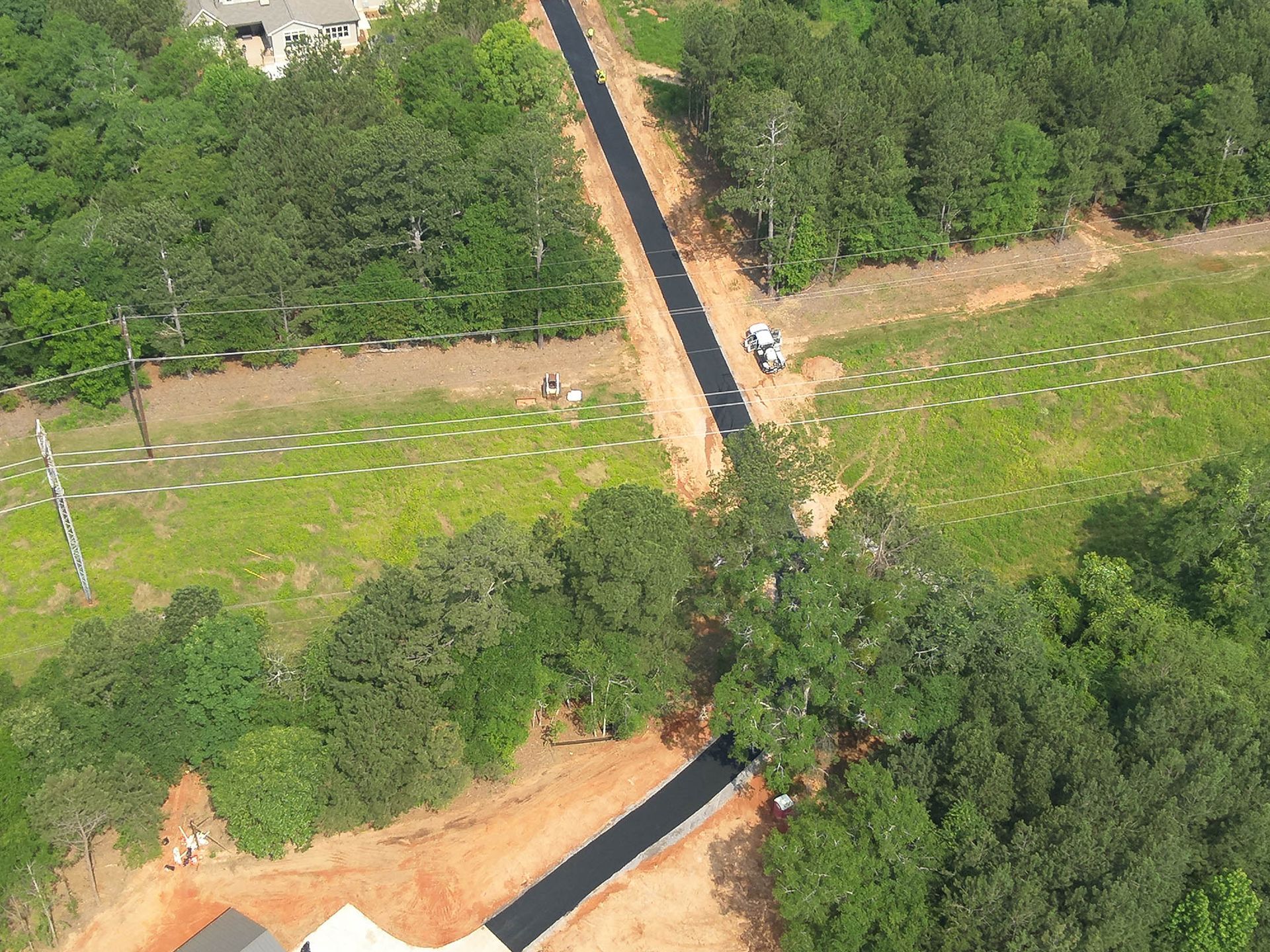 Aerial view of a newly paved road winding through a green wooded area.