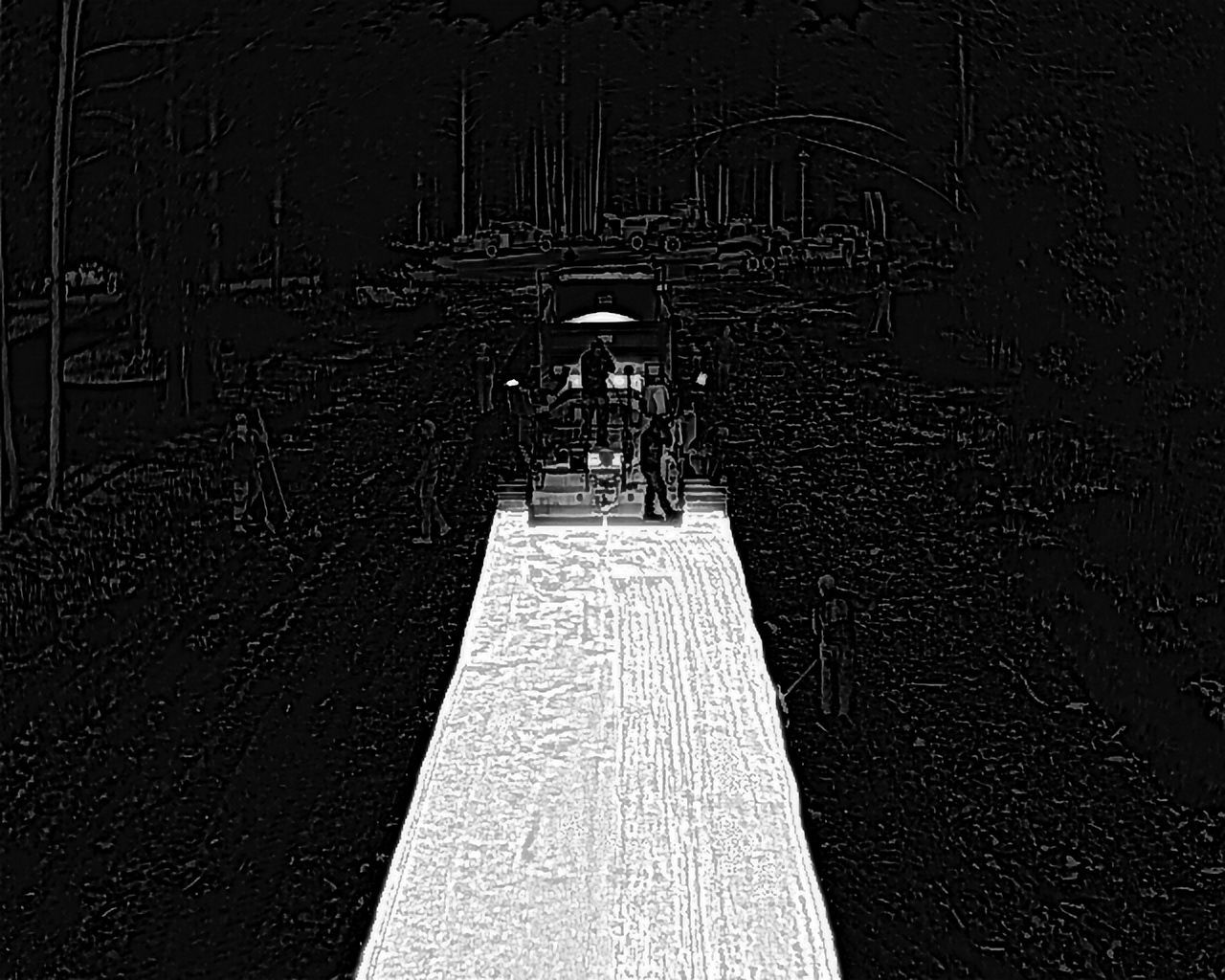 A cart on a snowy path is surrounded by trees. People stand on the cart.