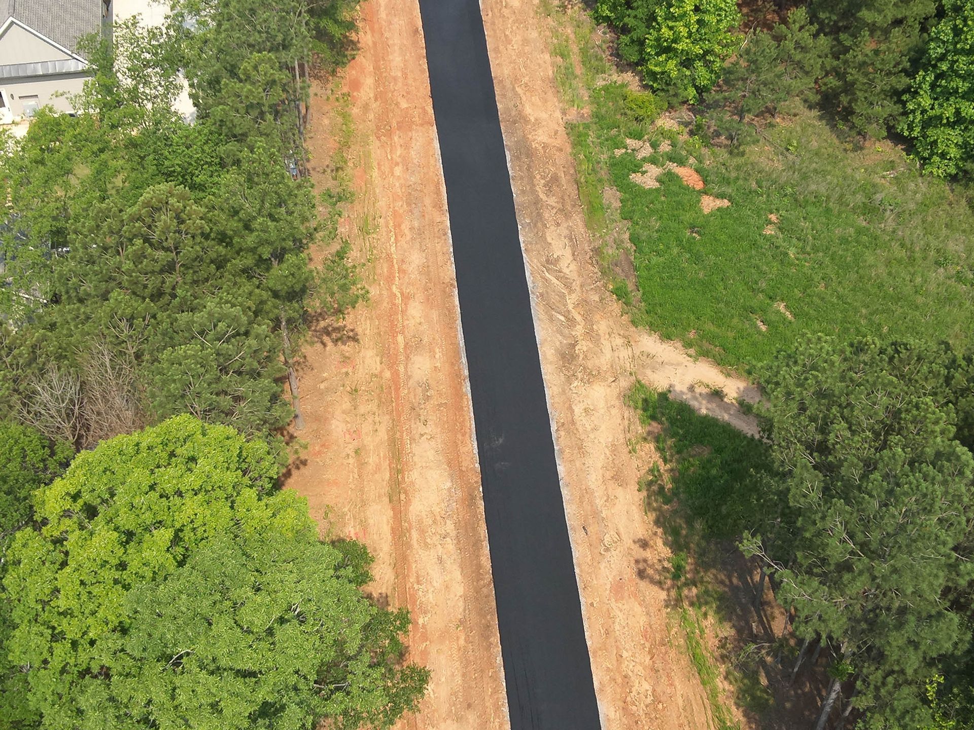 Aerial view of a paved pathway bordered by trees and grassy areas.