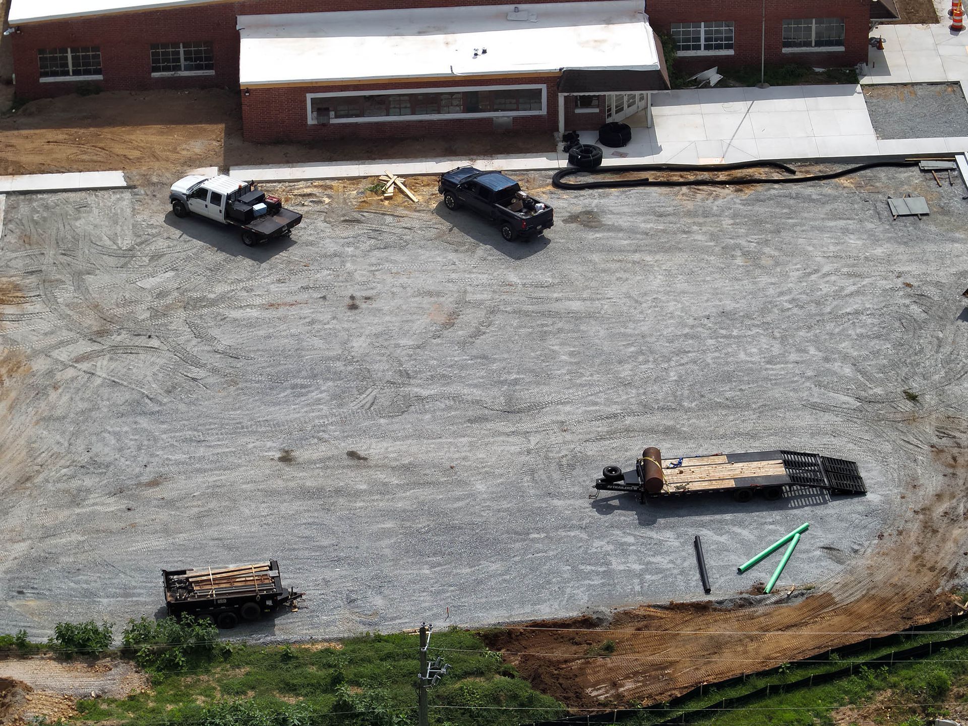 Construction site with trucks, building, and gravel lot.