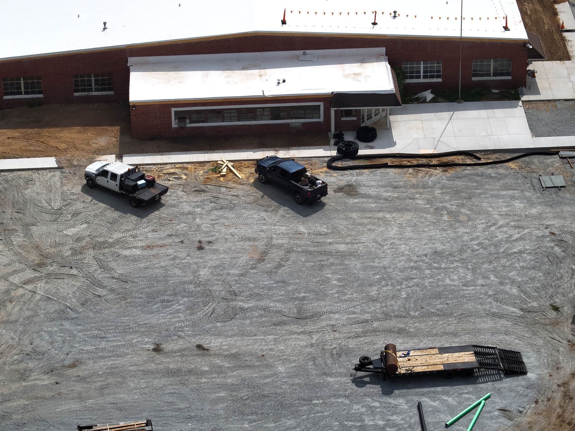 Construction site with a brick building and several work trucks parked on gravel.