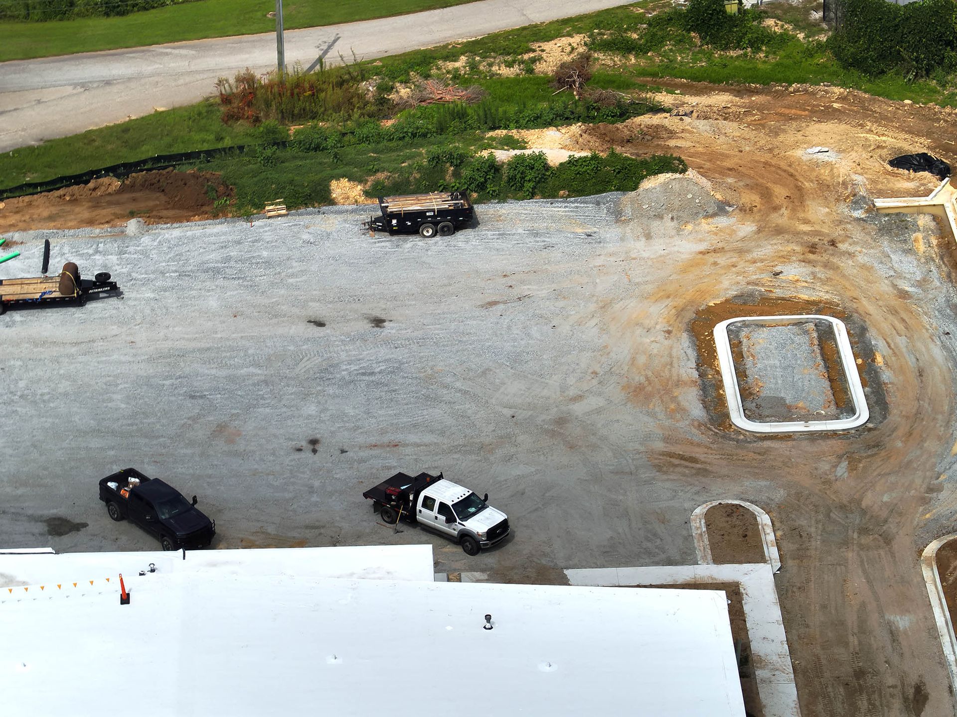 Construction site with gravel, trucks, and a building under construction.