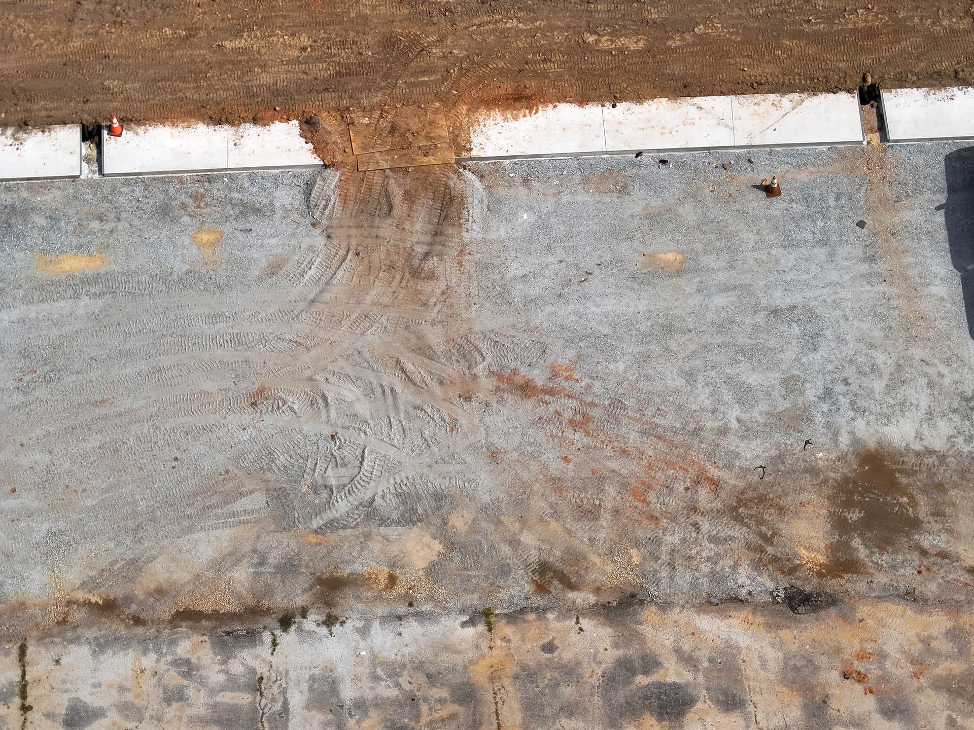 Brown soil spilling onto a gray concrete surface, with a white border.