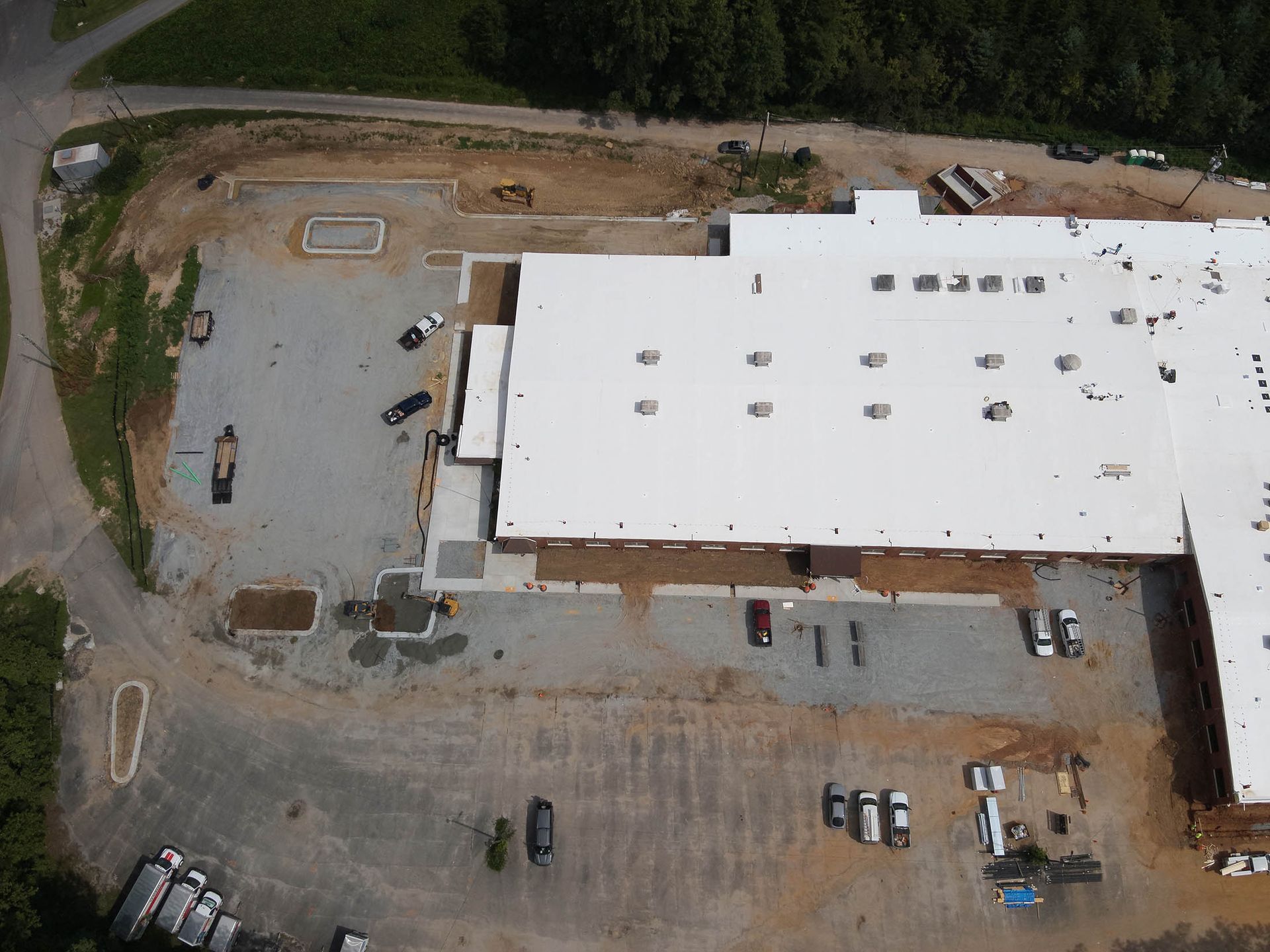Aerial view of a large commercial building with a white roof and parking lot.
