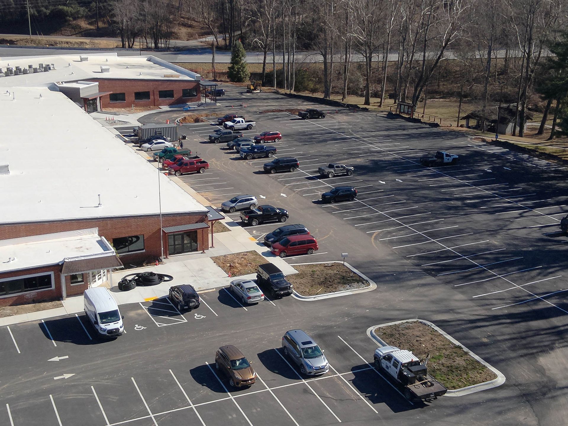 Cars parked in a mostly empty lot outside a one-story brick building on a sunny day.