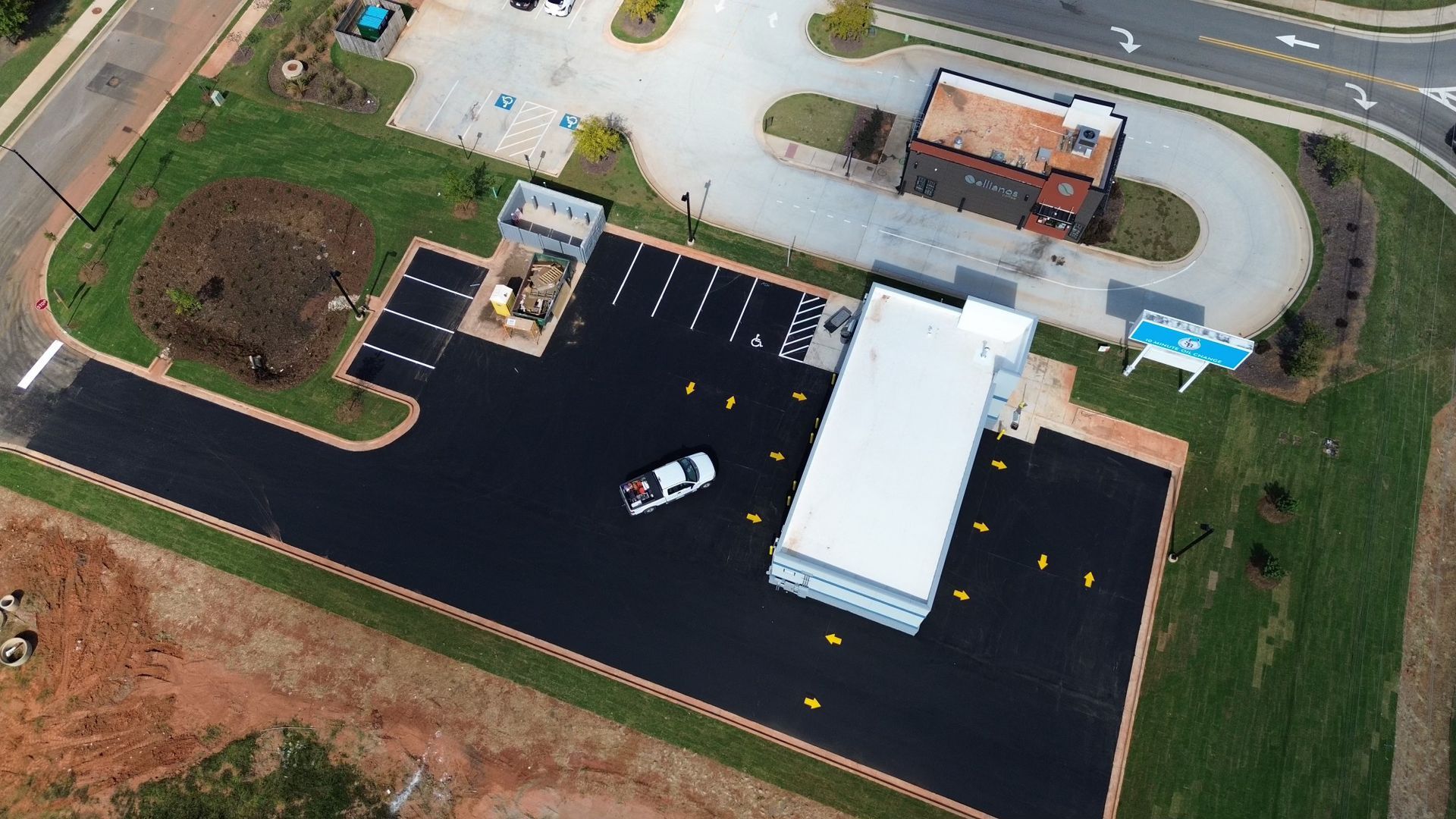 Aerial view of a building with a parking lot and a single white car parked.
