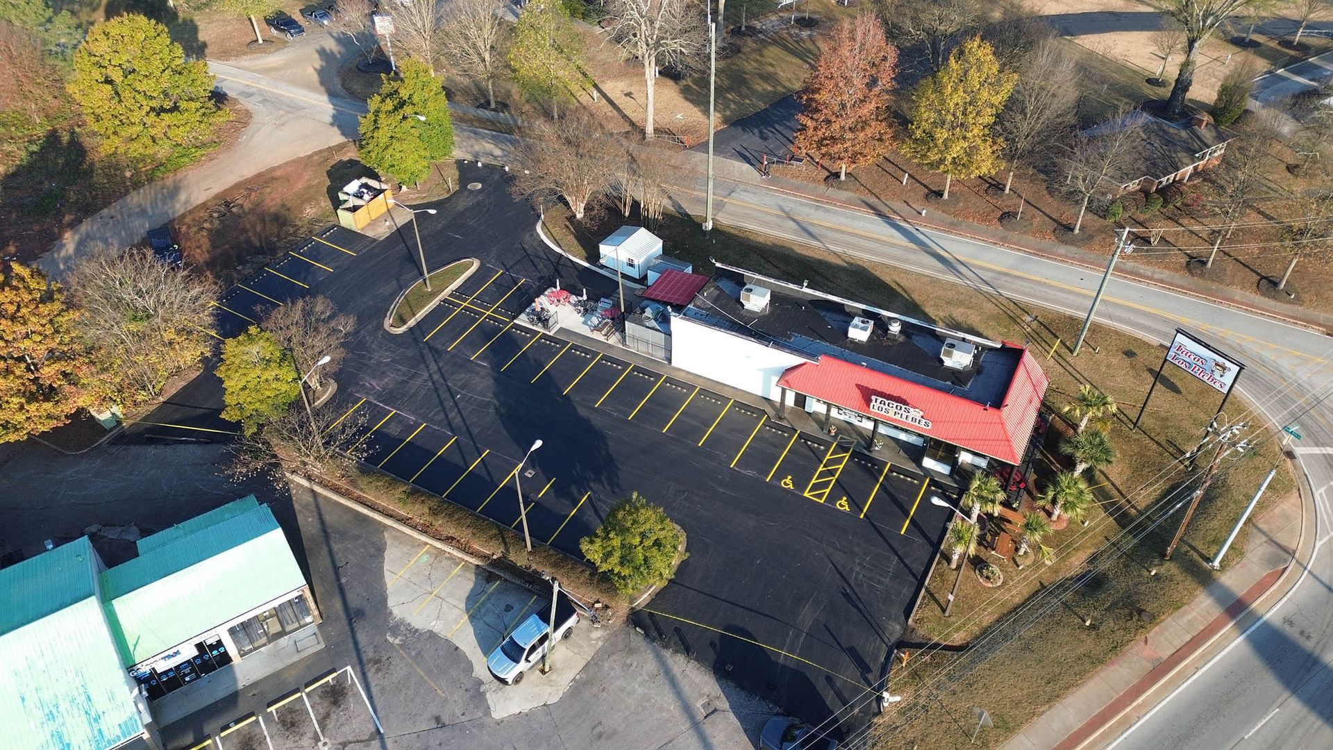 Aerial view of a restaurant with a red roof, surrounded by parking and trees.