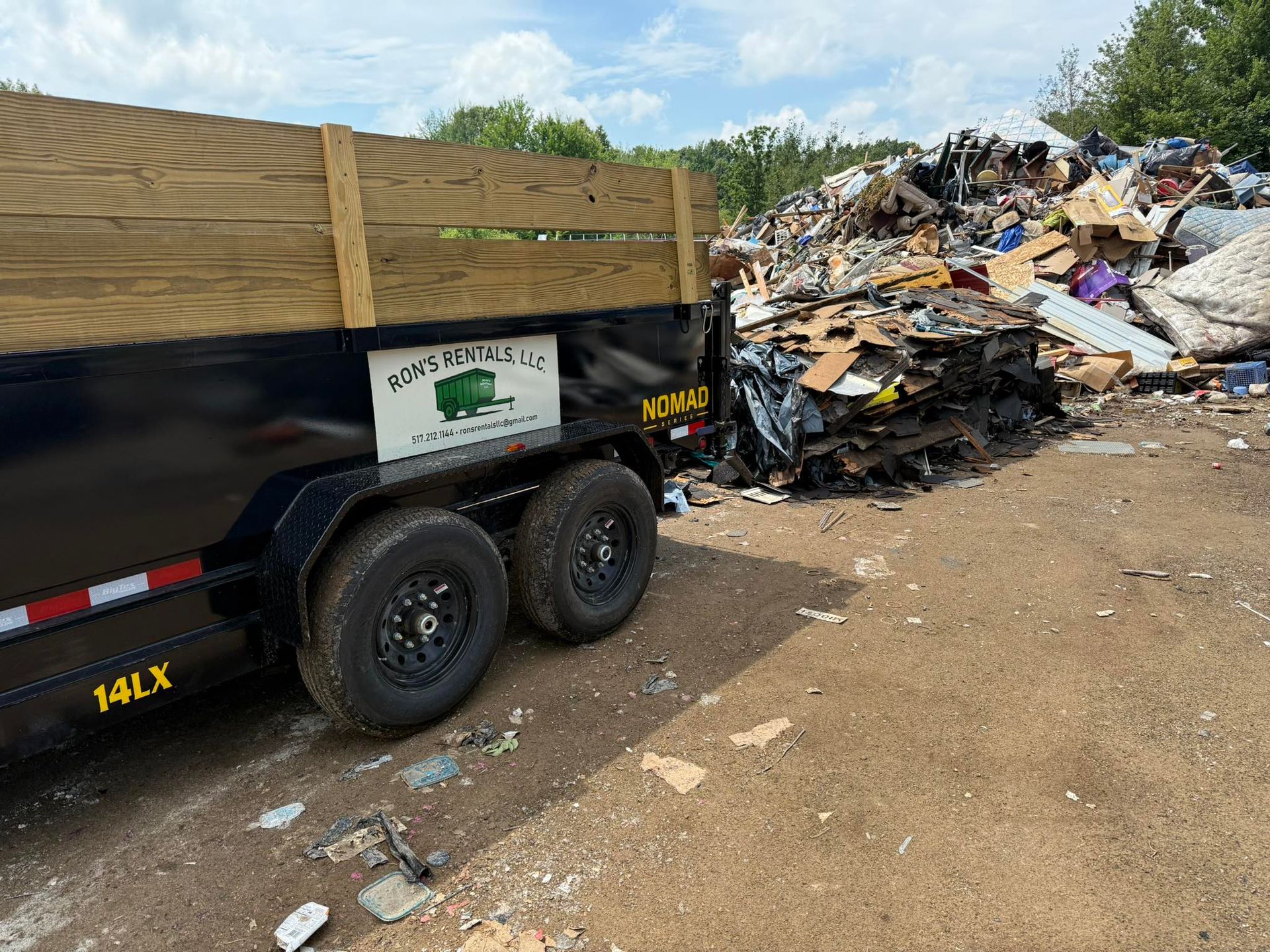 Black trailer next to a pile of construction debris at a landfill.