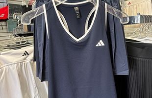 Learn more about Apparel A navy blue Adidas athletic tank top with white trim hanging on a plastic hanger in a retail store.