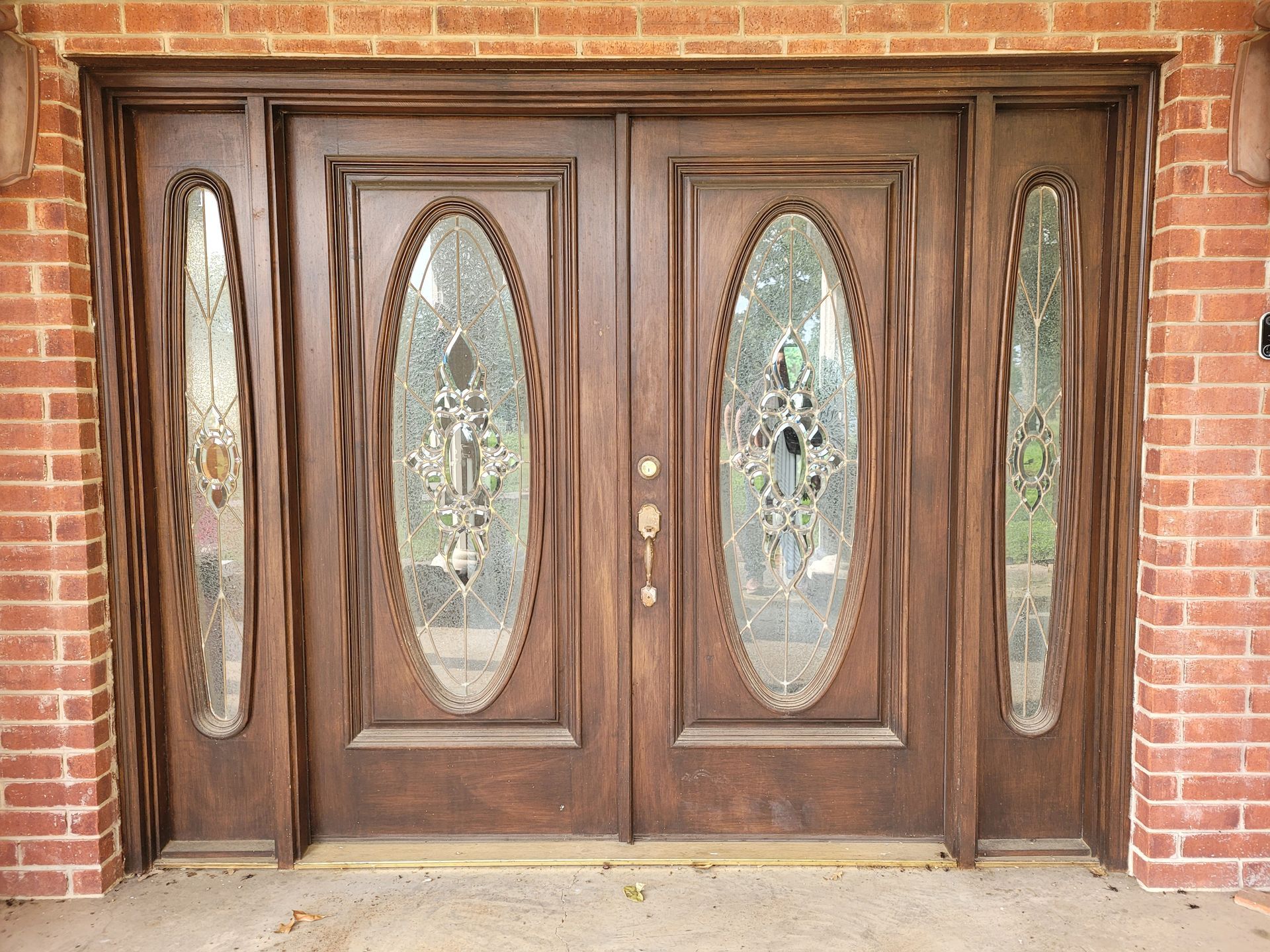 A large wooden door with oval windows on a brick wall