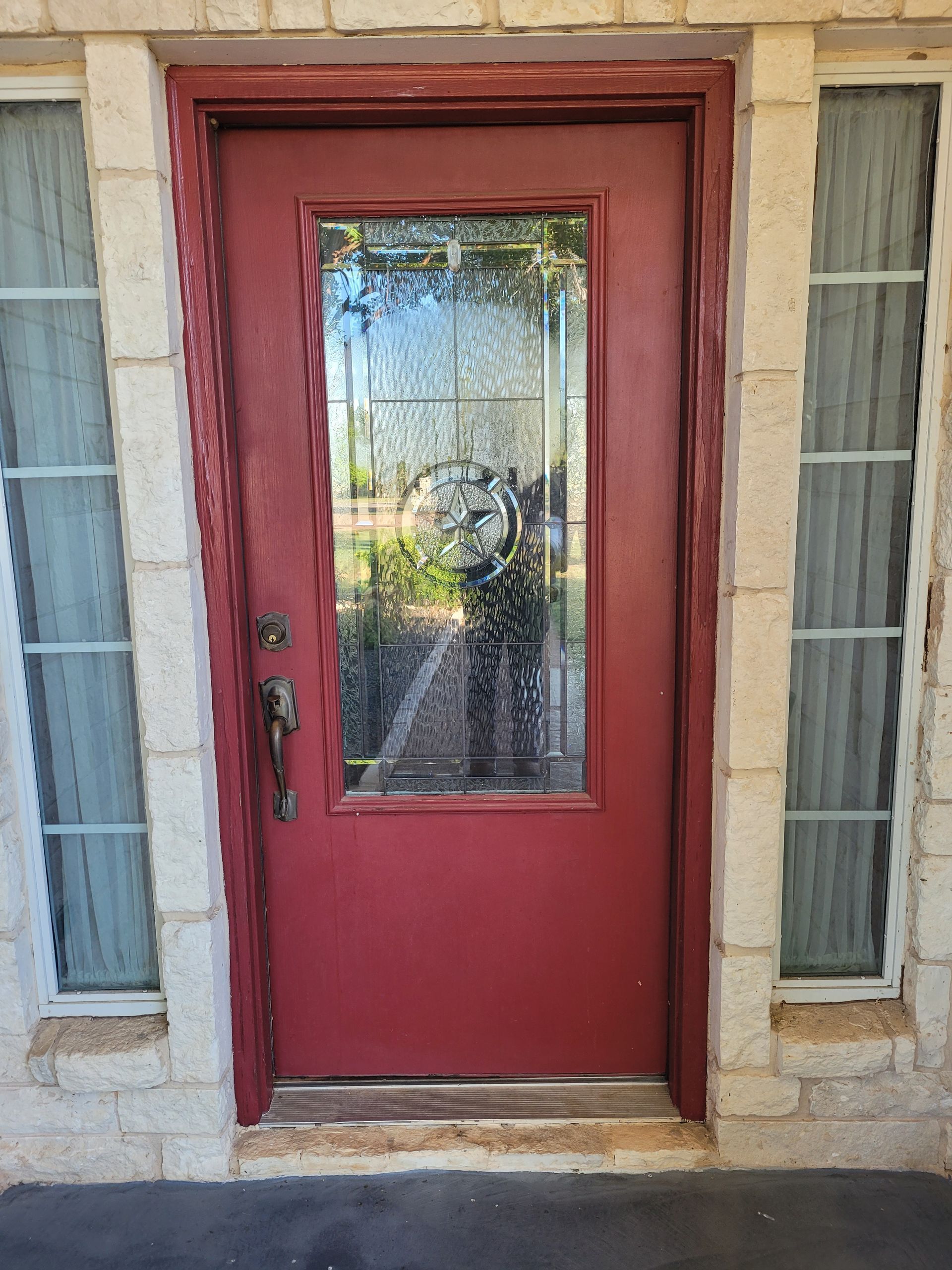 A red door with a glass window is on a brick building.