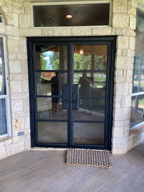 A patio with a black door and a rug on the floor