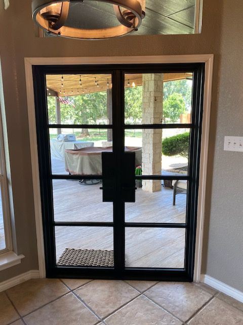 A room with a black door that looks out to a patio