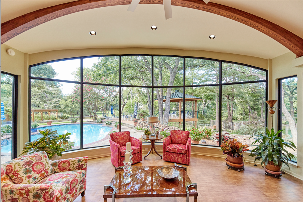 a living room with a lot of windows and a pool in the background
