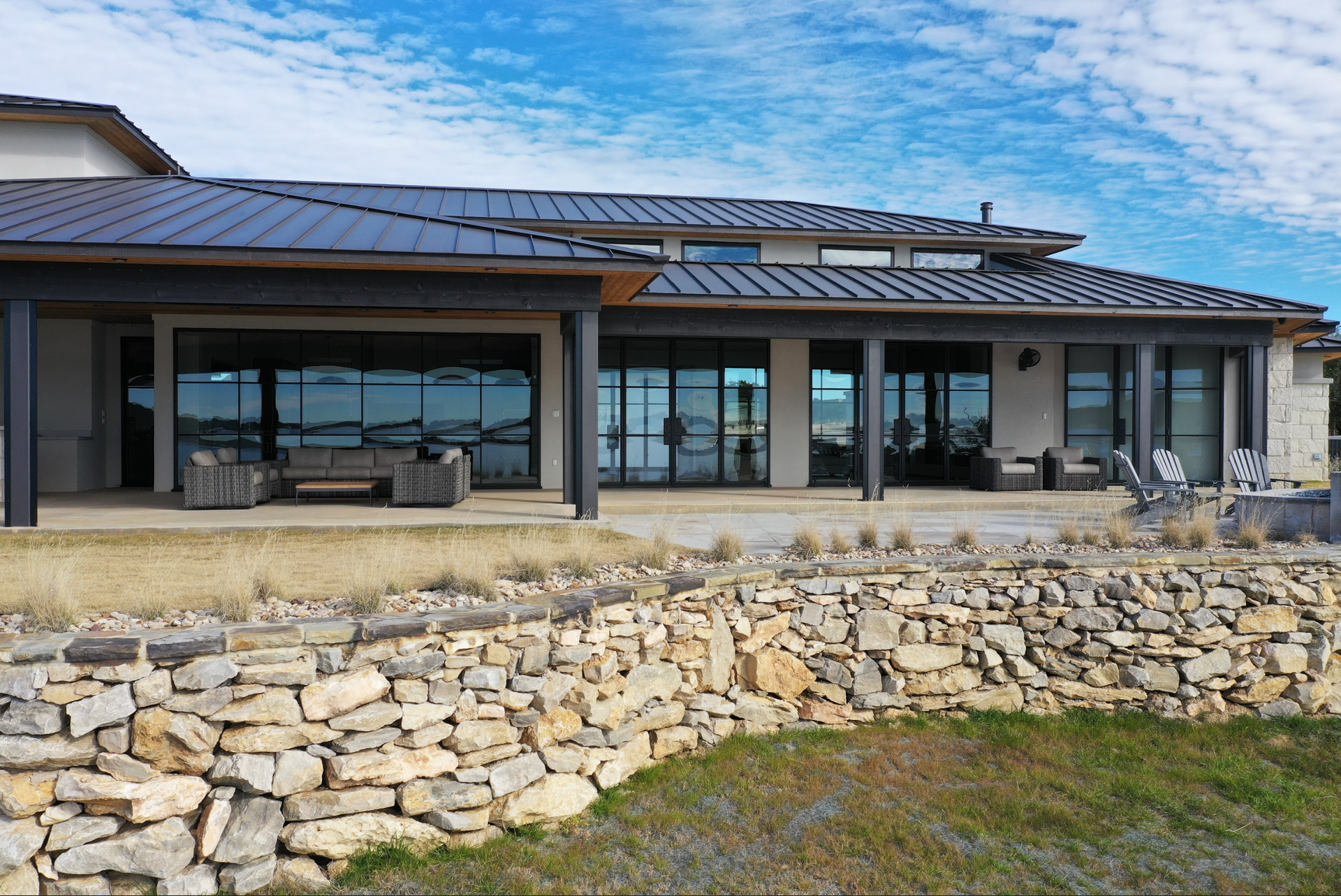 a large house with a lot of windows and a stone wall in front of it
