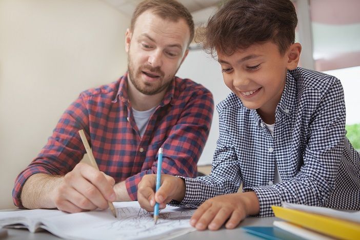 A man is helping a young boy with his homework.