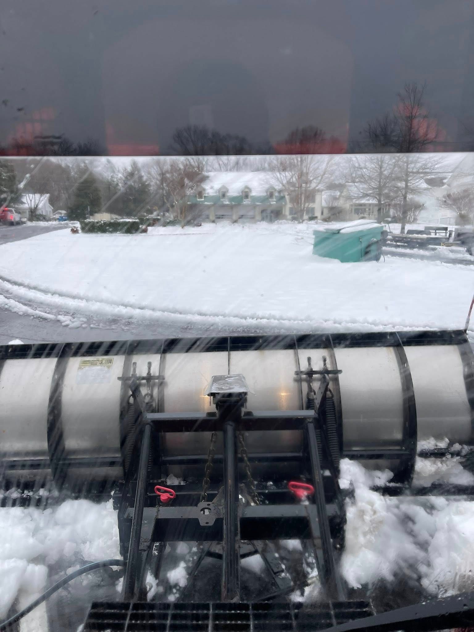 View from inside a snowplow clearing a snowy parking lot.