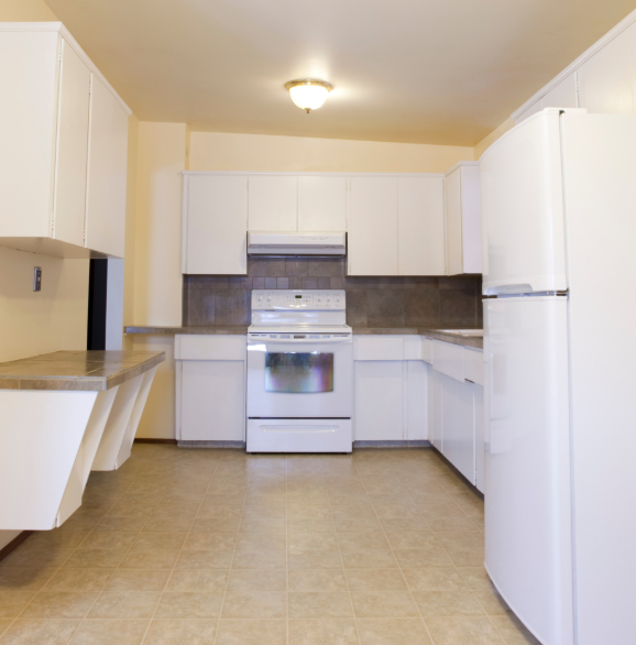A kitchen with white cabinets, a white stove, a white refrigerator, tan floors, and a built-in counter.