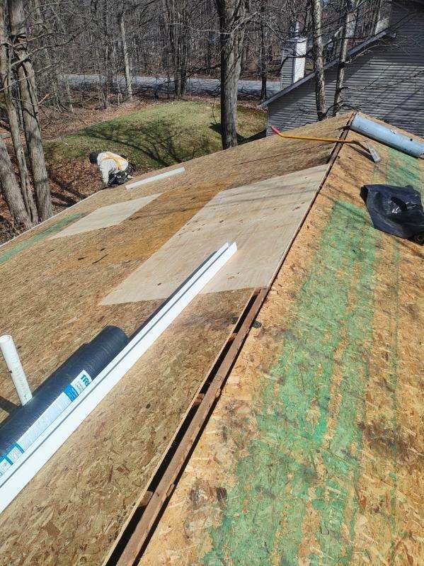 A worker installs plywood sheeting on a residential roof deck during a renovation project.