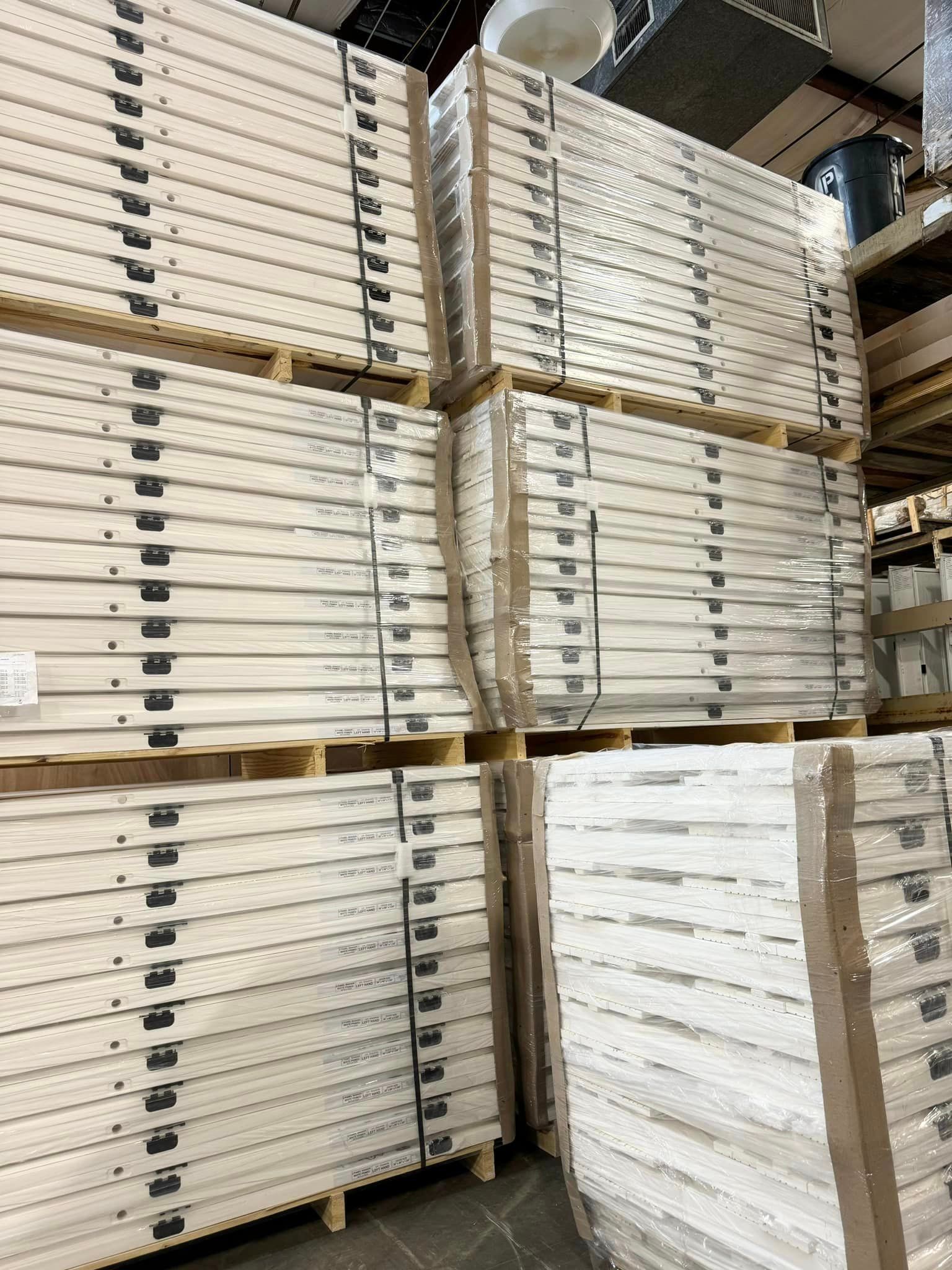 A warehouse filled with many white pallets stacked on each other