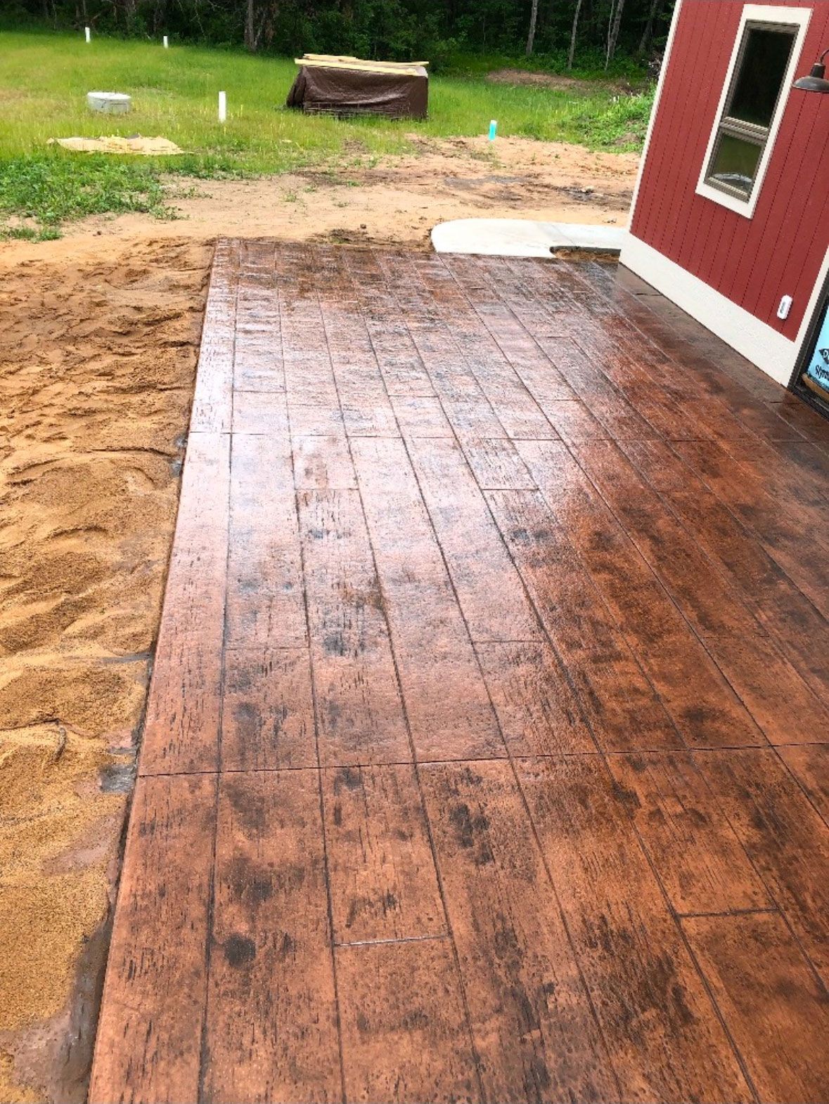 A decorative concrete patio with a red barn in the background