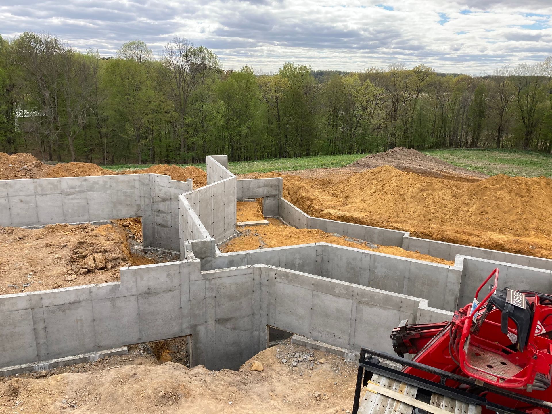 A concrete foundation is being built in a field with trees in the background.