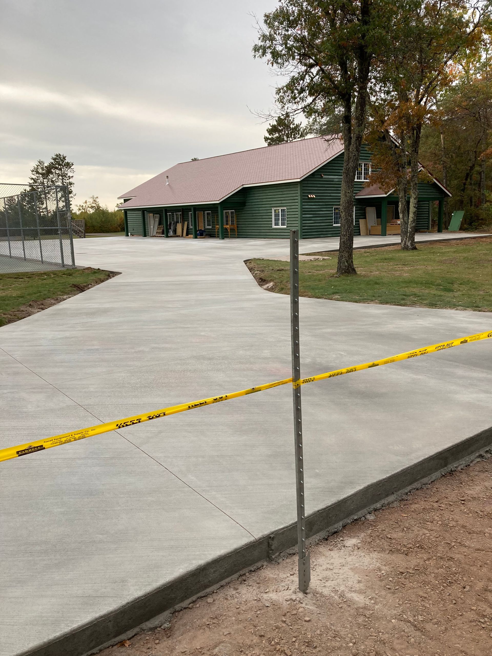 A concrete driveway is being built in front of a log cabin.