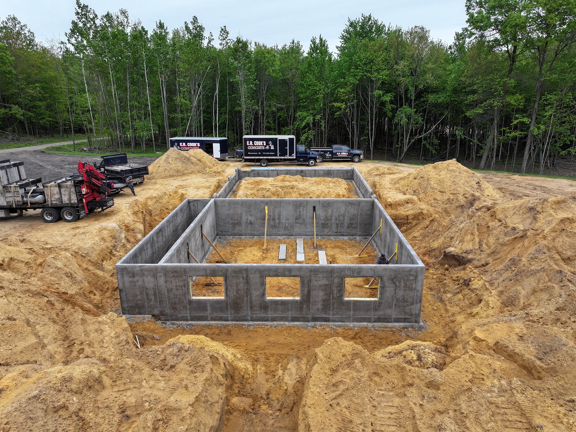 A large concrete foundation is being built in a dirt field.