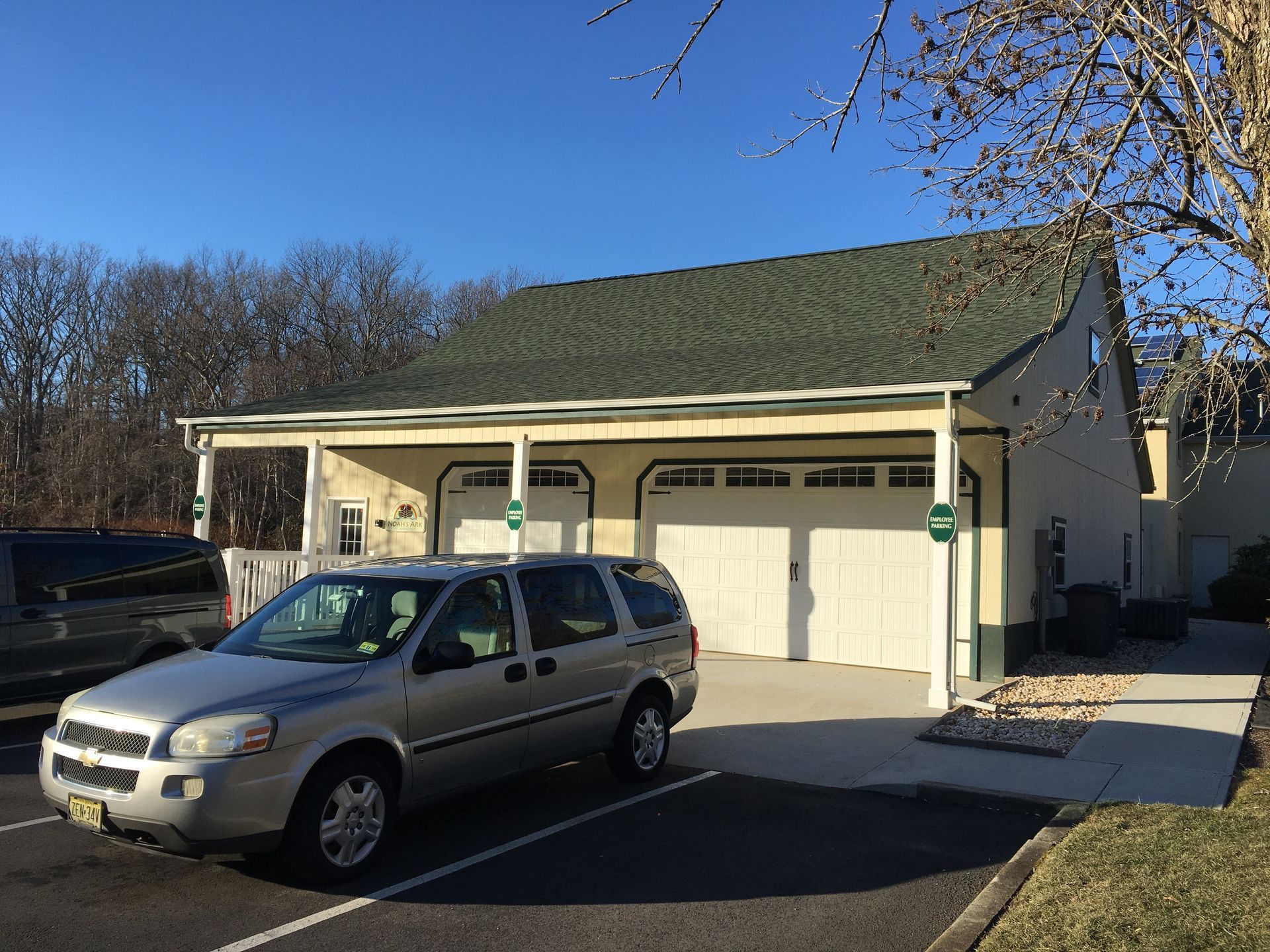 Silver SUV parked in front of a beige house with a green roof and attached garage.