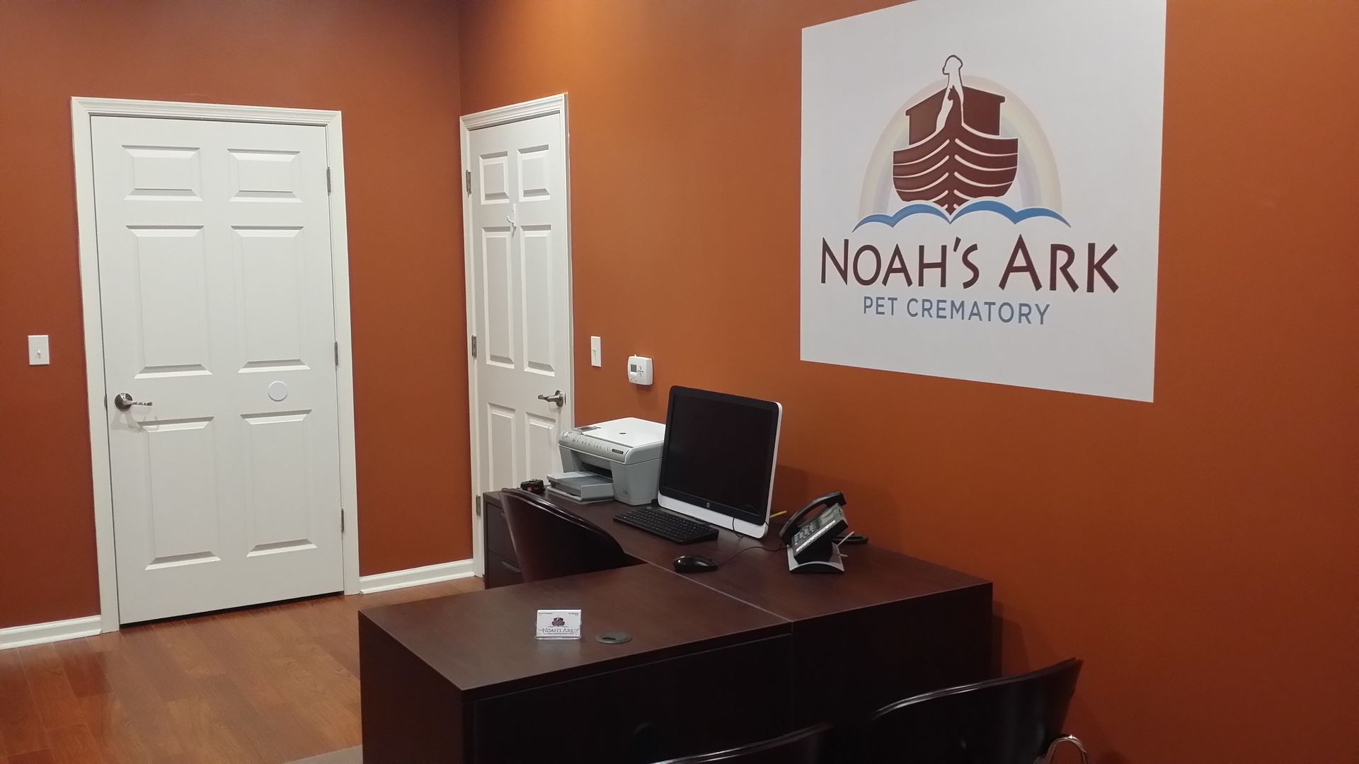 Office reception desk with computer in front of a Noah’s Ark sign on an orange wall
