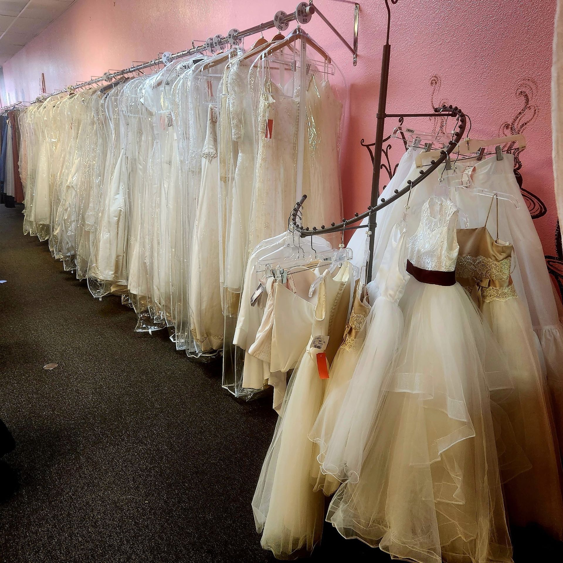 A row of white dresses hanging on racks in a store