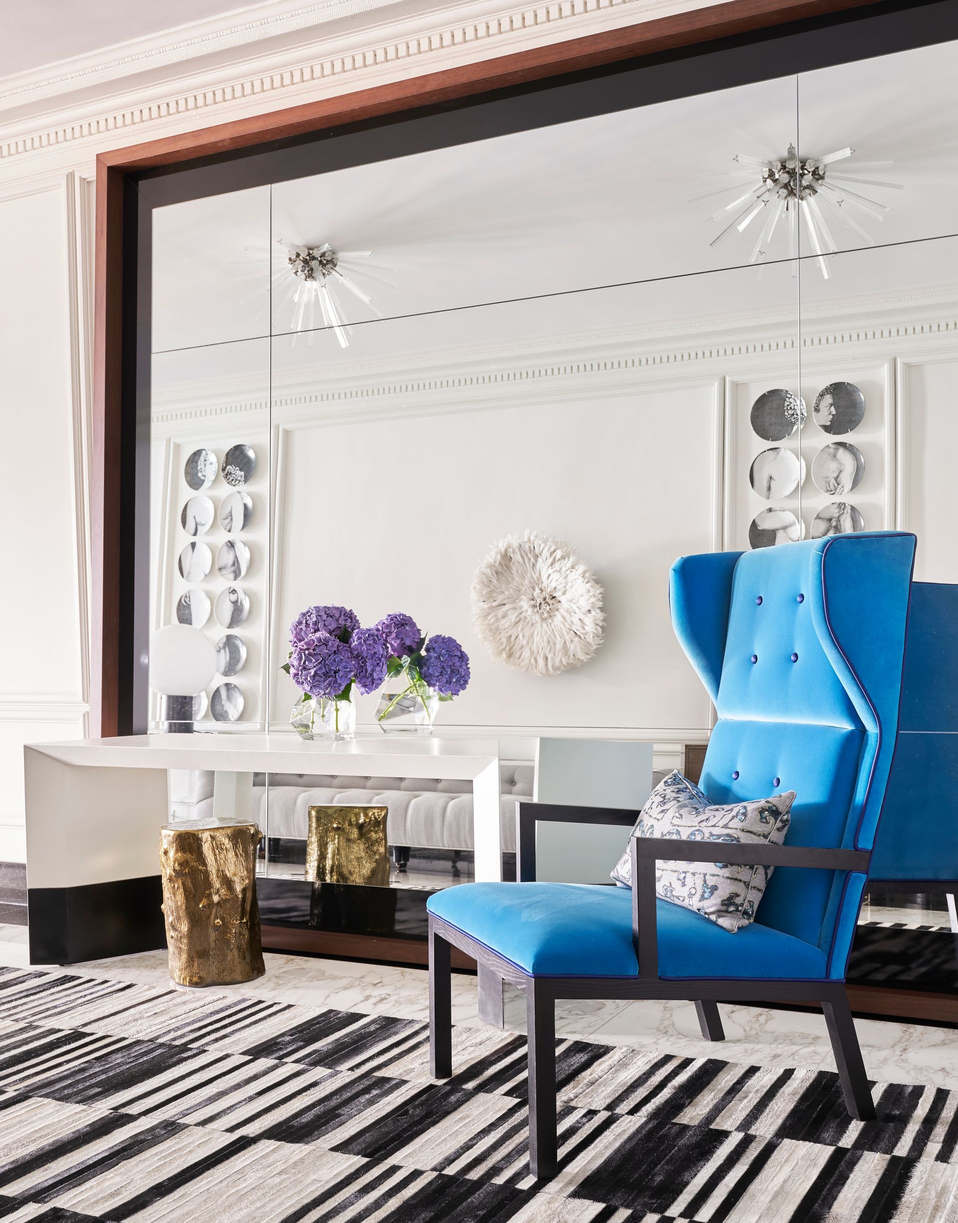 A living room with a blue chair and a black and white rug.
