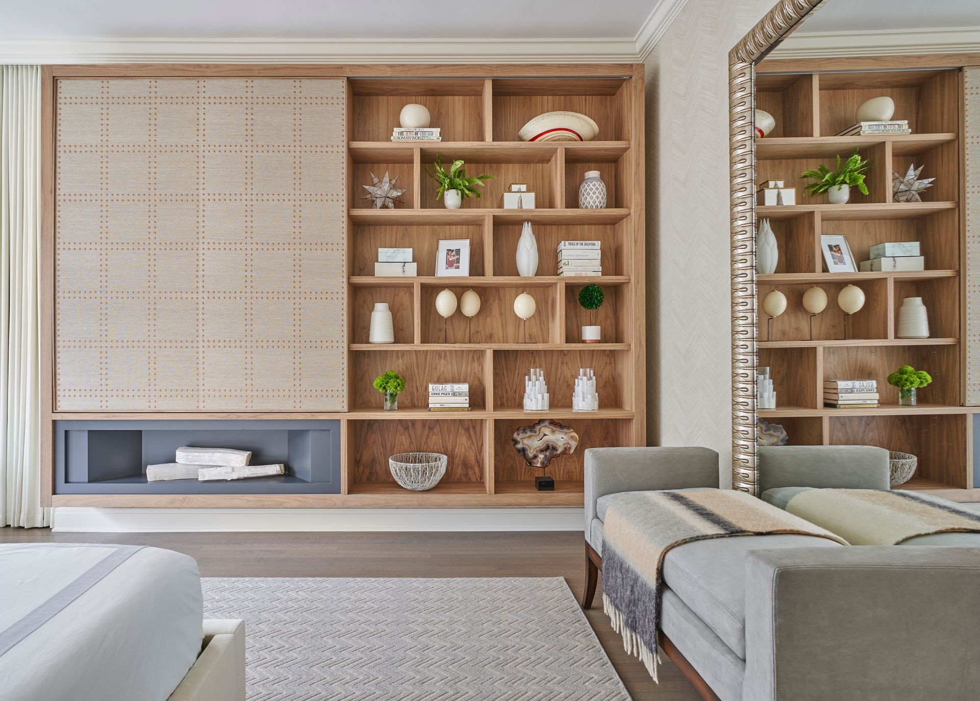 A living room with a couch, shelves, and a mirror.